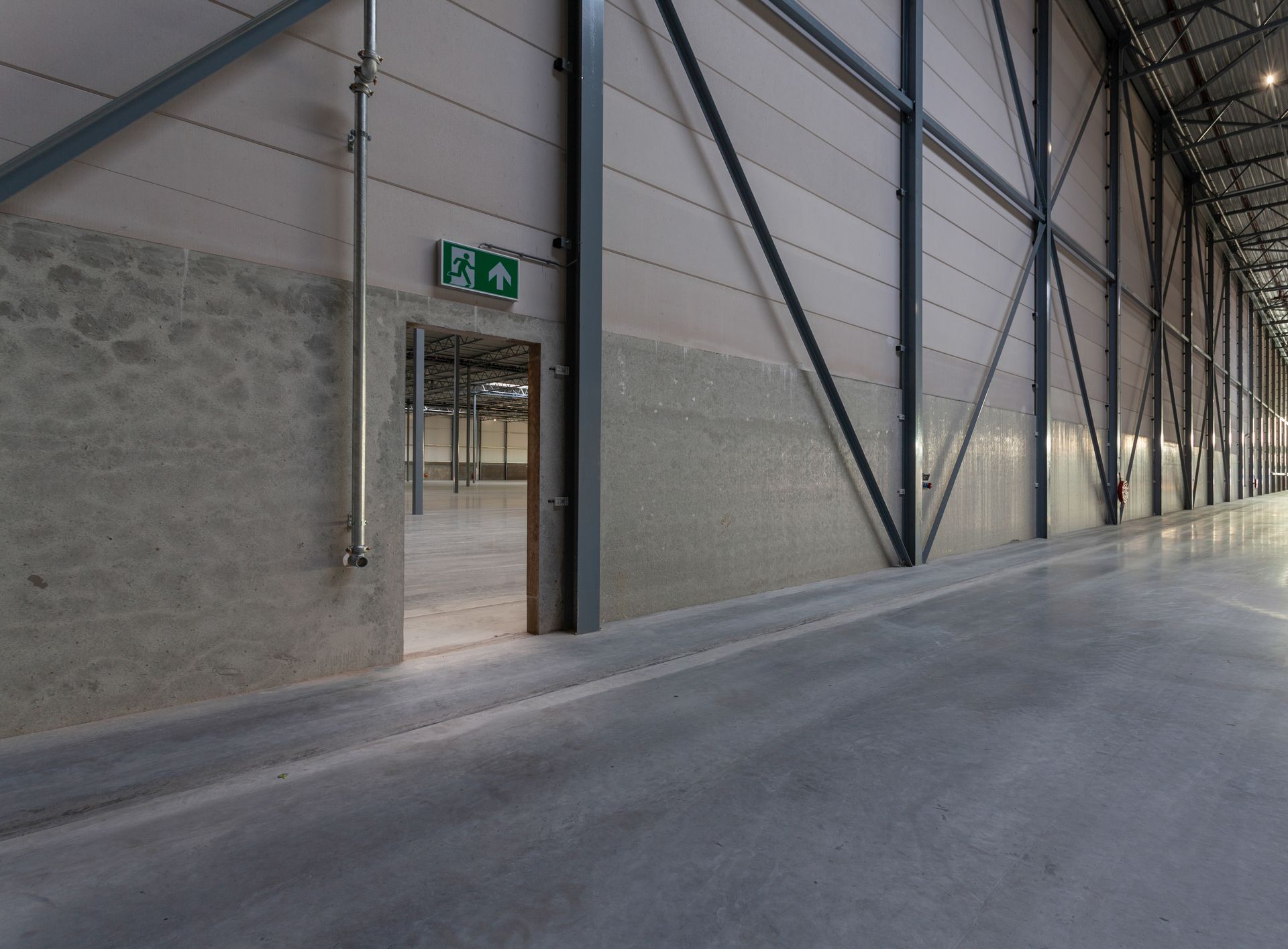 White industrial crane on tracks inside a building with a glossy floor and white railings.
