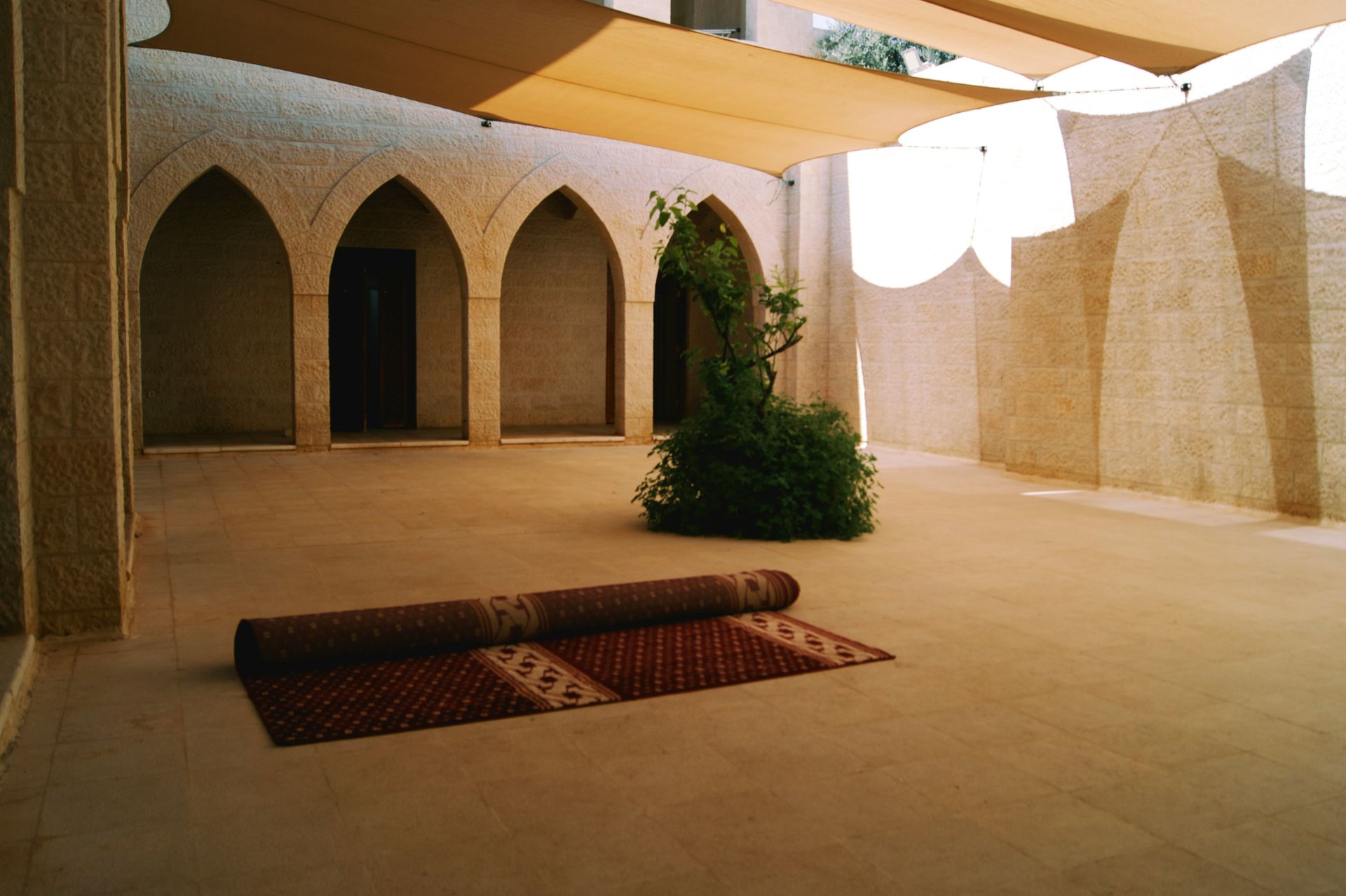 Interior of a chapel prepared for an event, with rows of white-covered chairs, a podium, and arched windows.