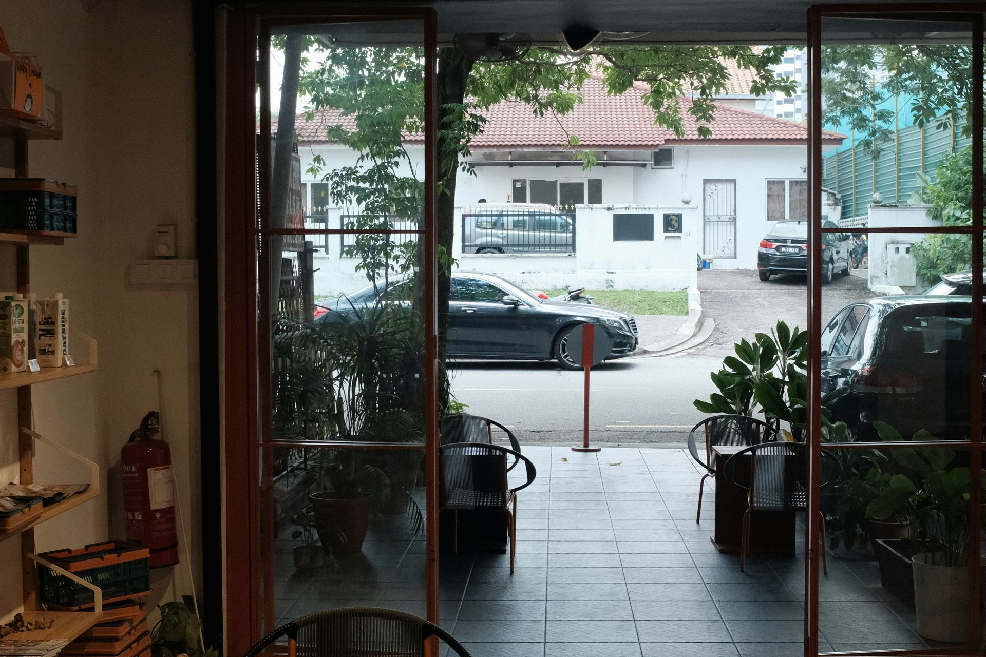 Long hallway with city view, wooden floor, bench, door, potted plant, and large windows.