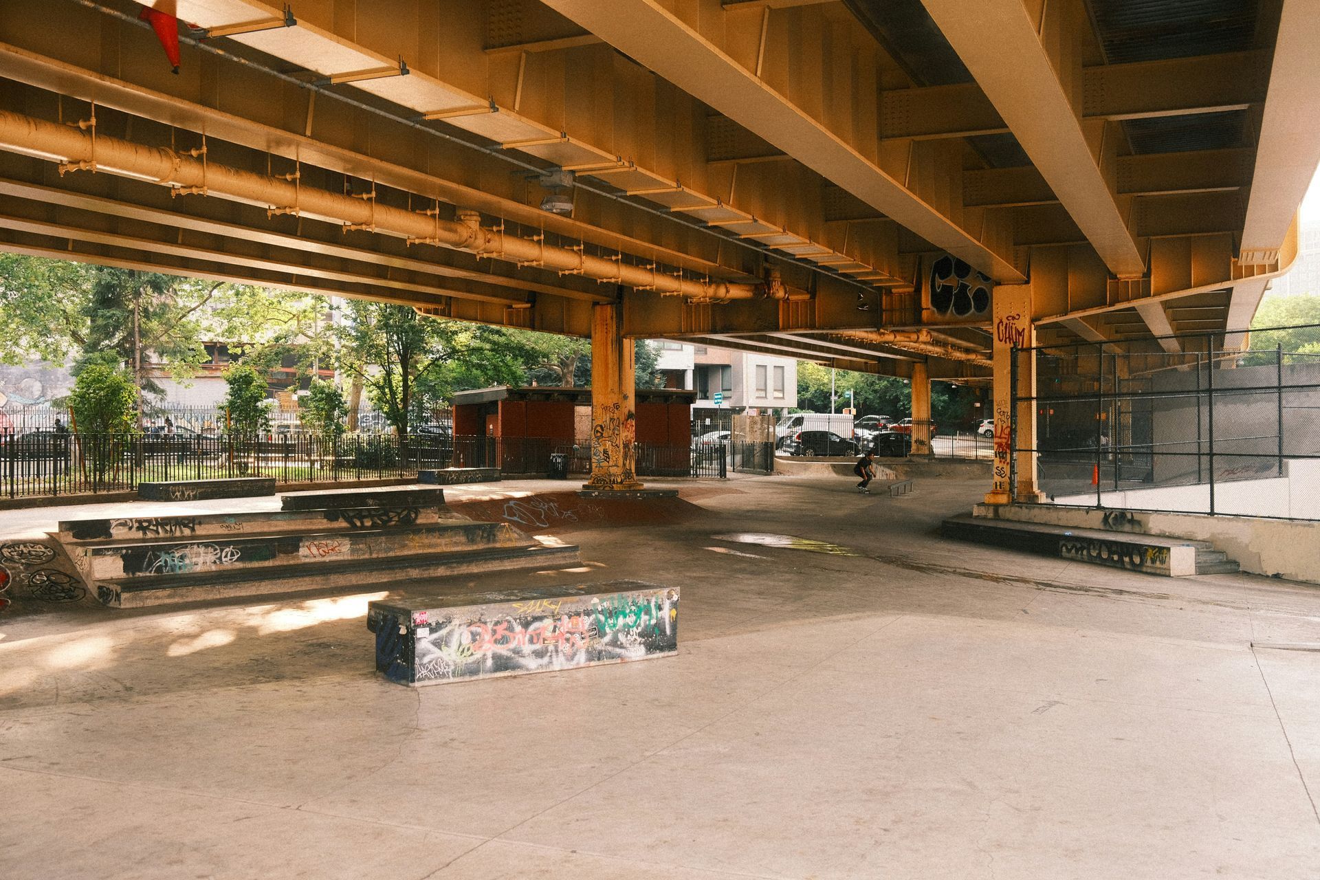Wooden bookcase in a sunlit home office with desk, chair, and large windows overlooking a city.