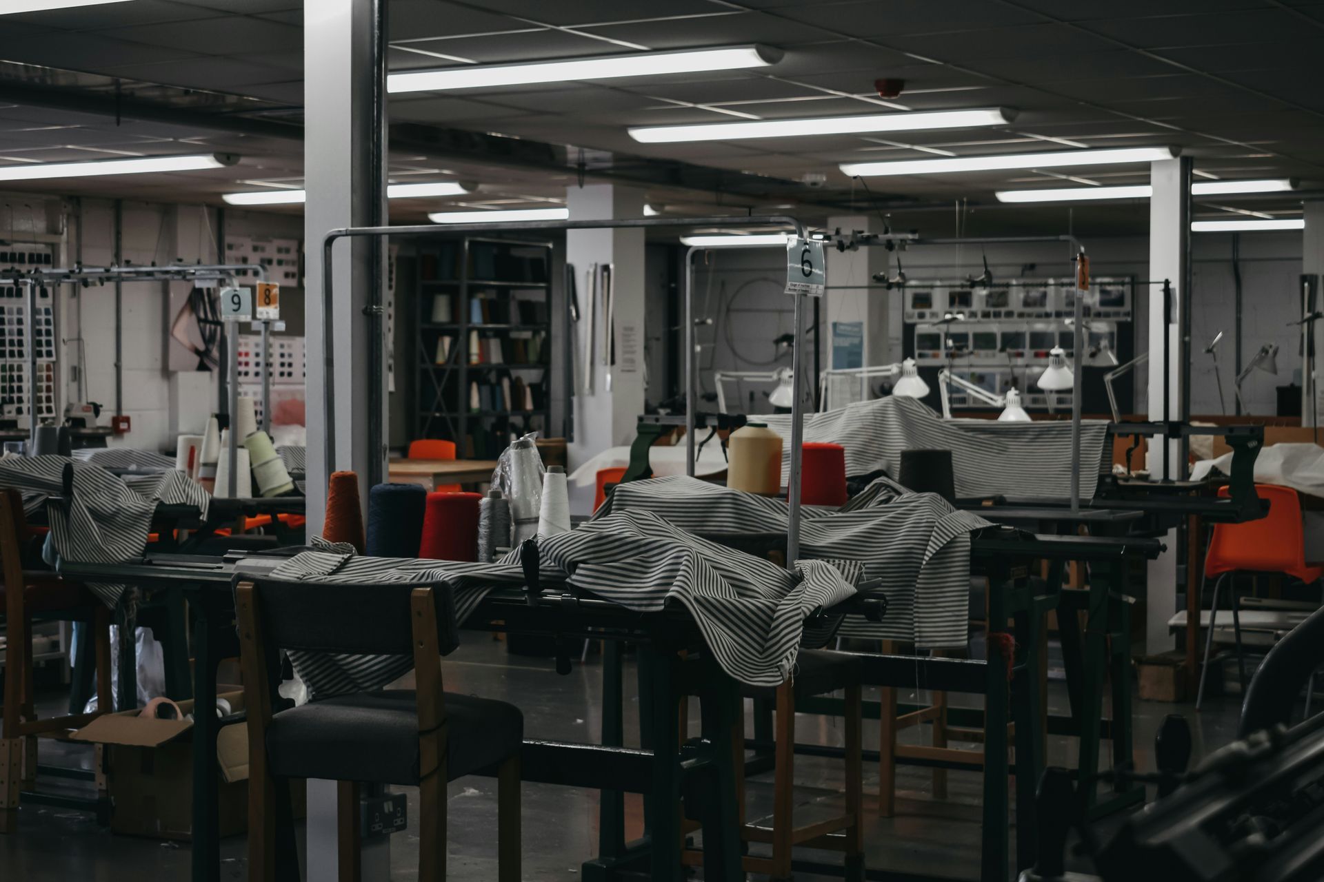 Interior of a textile workshop with tables, sewing supplies, and a few people.