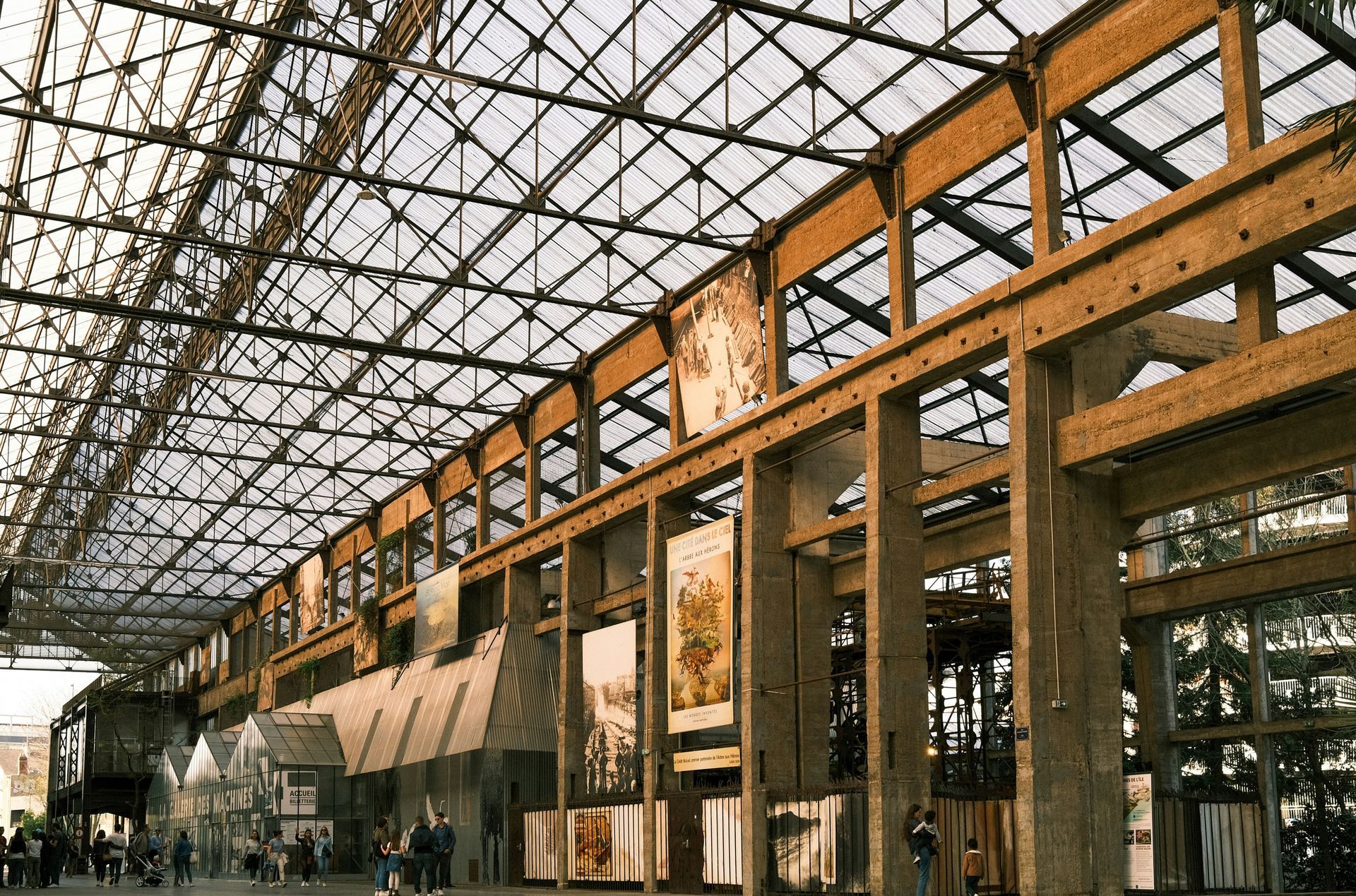 Interior view of a large hall with a glass ceiling and wooden beams; artwork hangs on the walls.