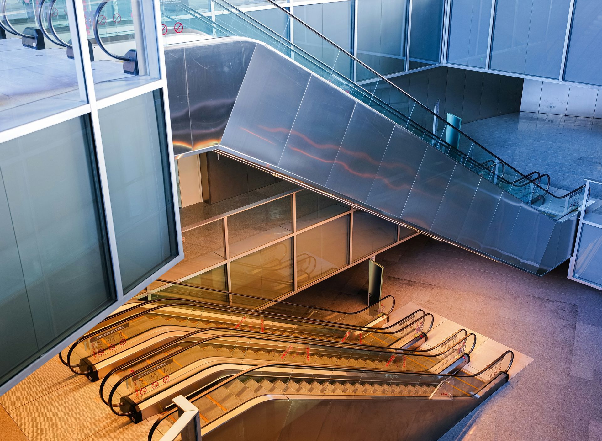 Escalators in a modern building with metallic walls and railings, a high-angle shot.