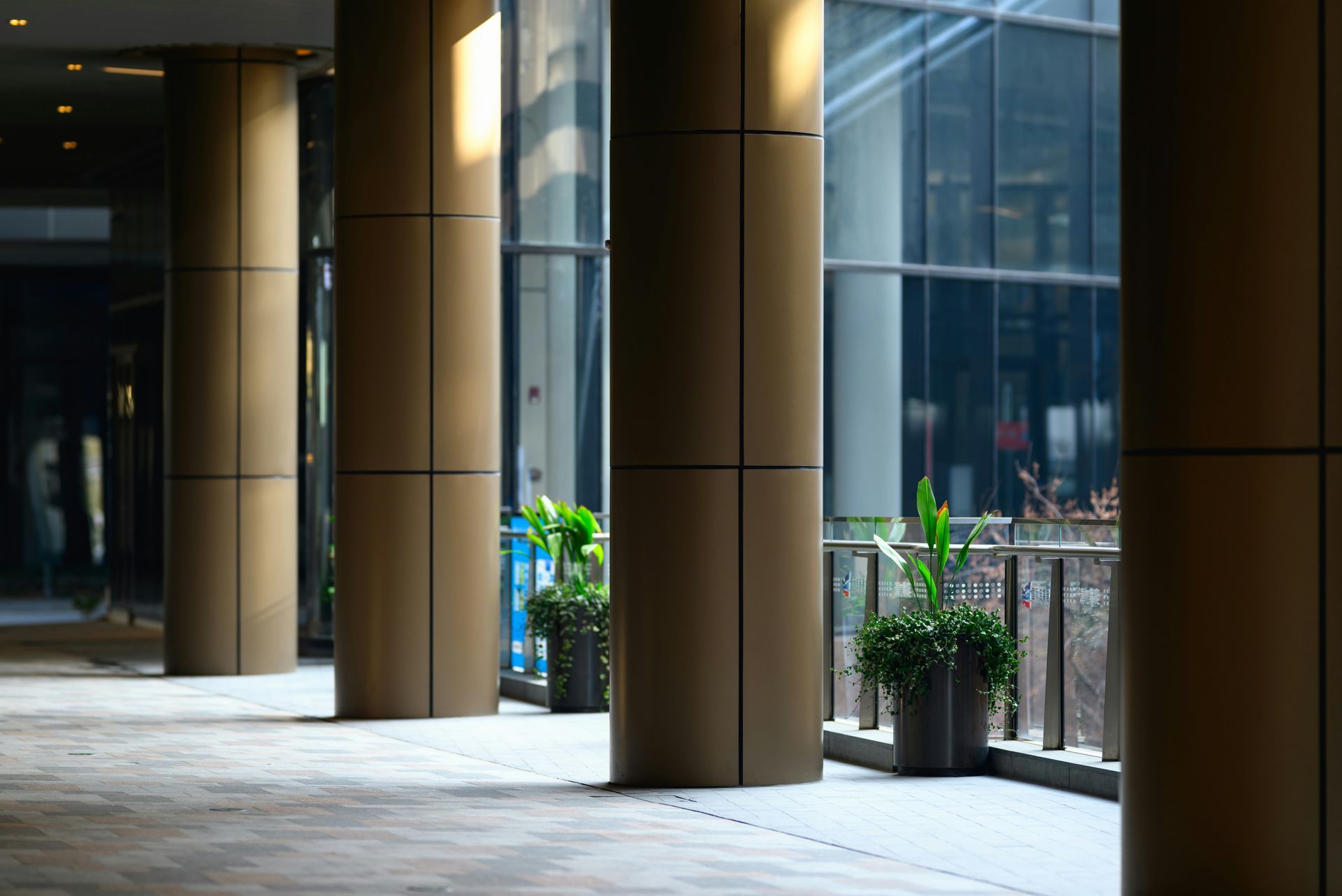 Columns on a building's exterior. Beige with black accent lines, plants, and glass windows.
