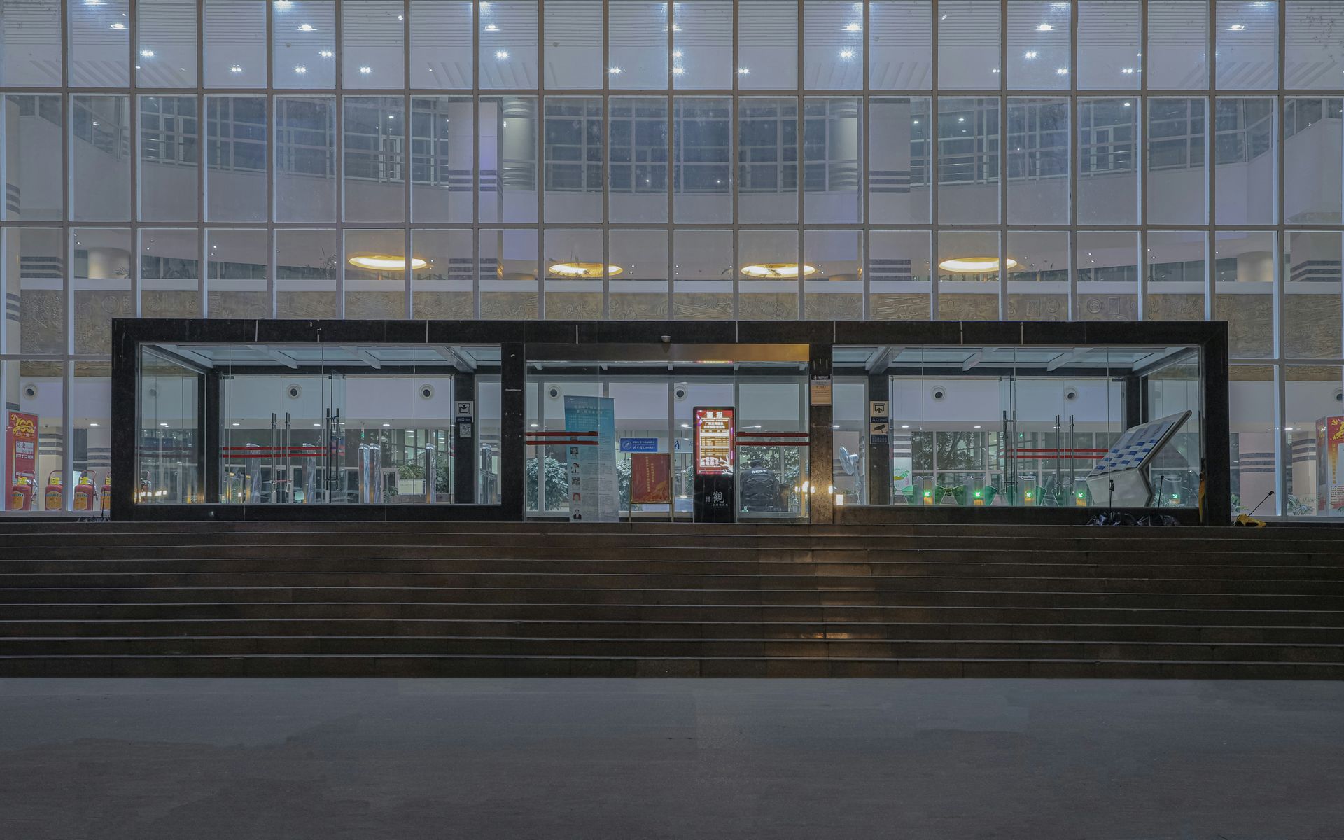 Front view of a modern building entrance with glass walls and a set of steps leading up.