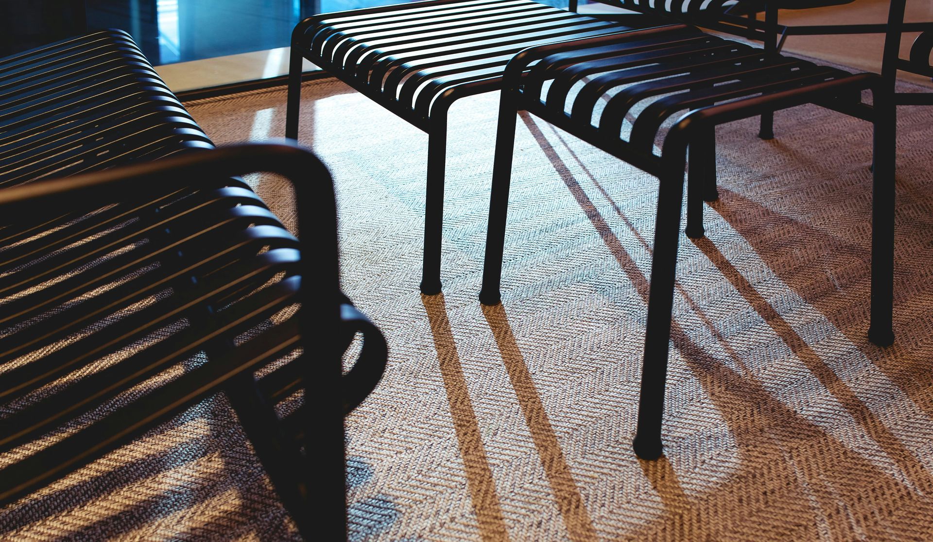 Black chairs with woven seats cast shadows on a textured rug.