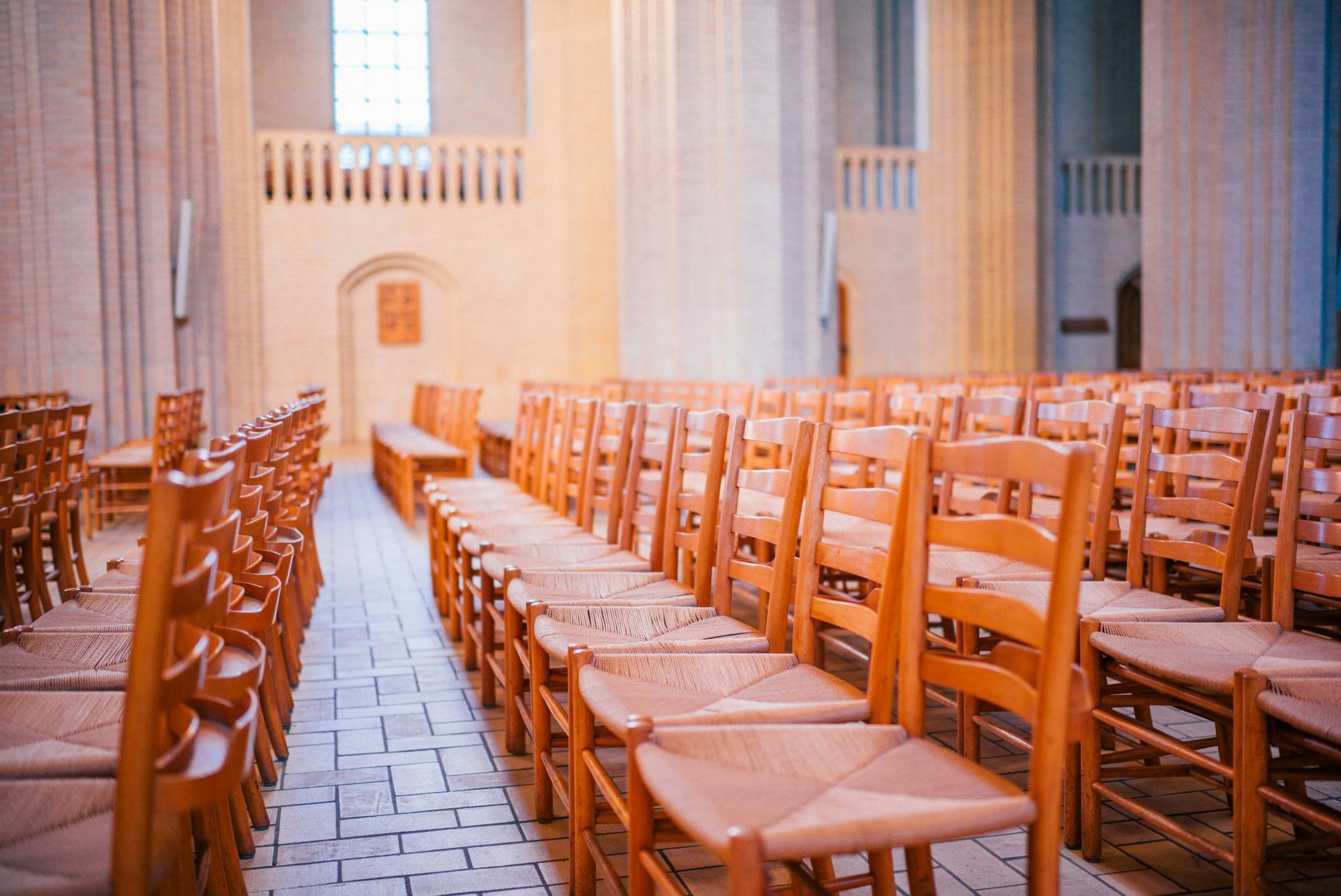 Rows of wooden chairs in a light-filled church interior.