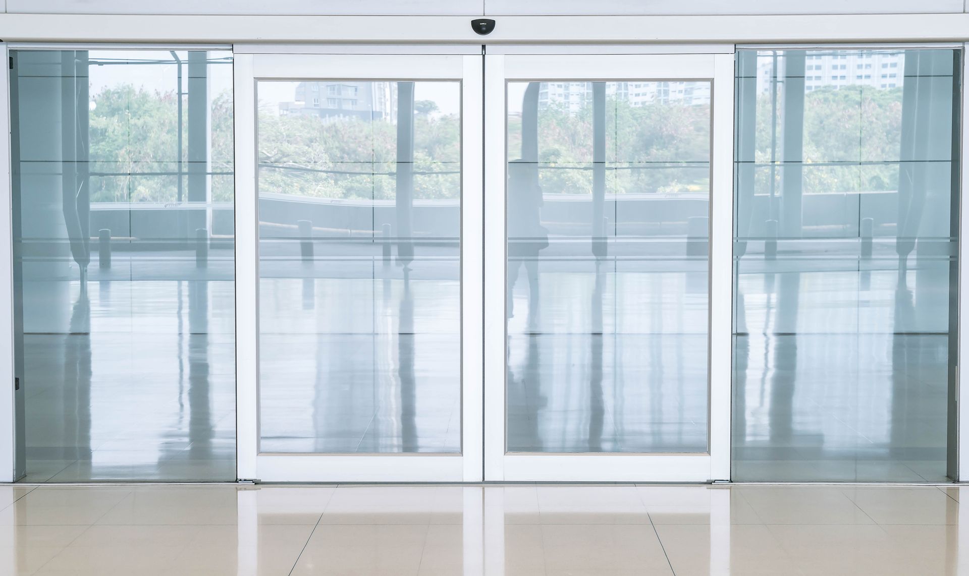Sliding glass doors with white frames, in a bright, modern building.