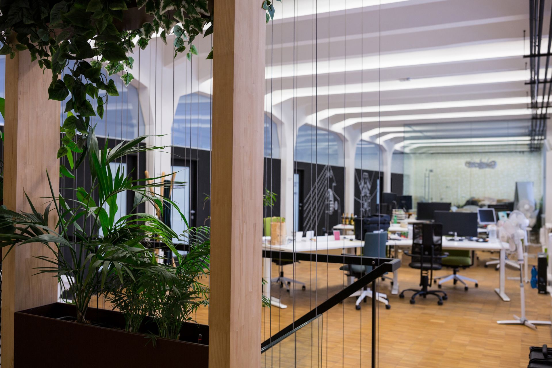 Bright office space with plants, desks, and arched windows.