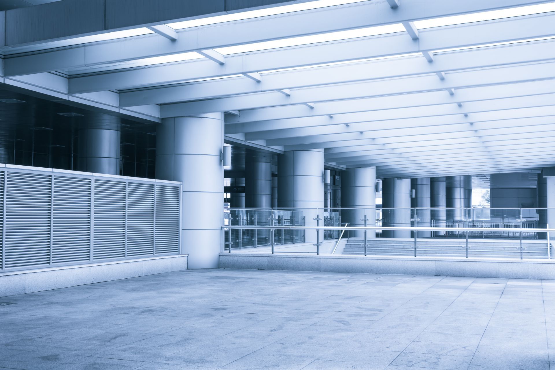Blue-toned architectural space with columns, glass railings, and decorative panels.