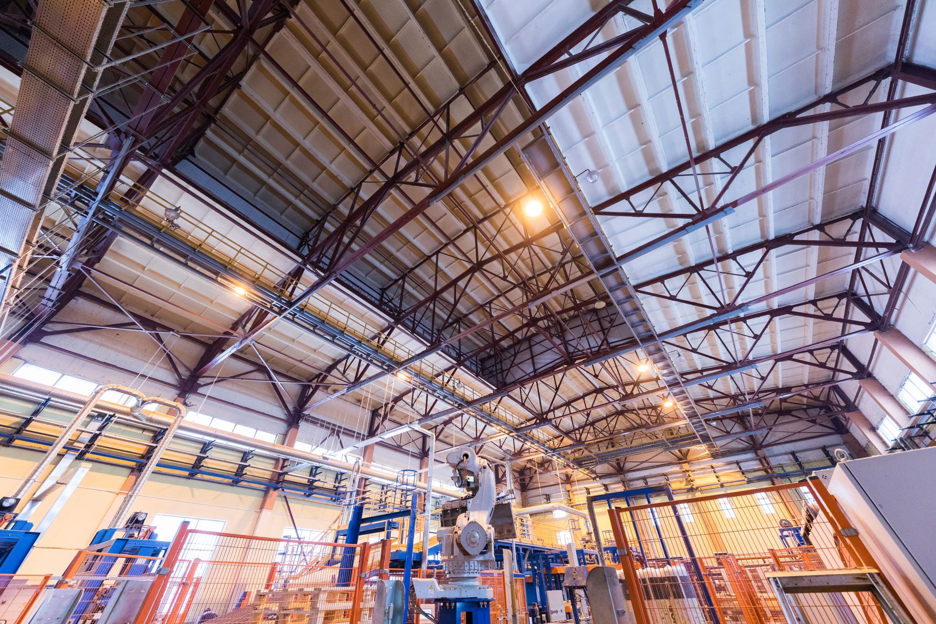 Inside a factory, looking up at the metal roof and support beams.