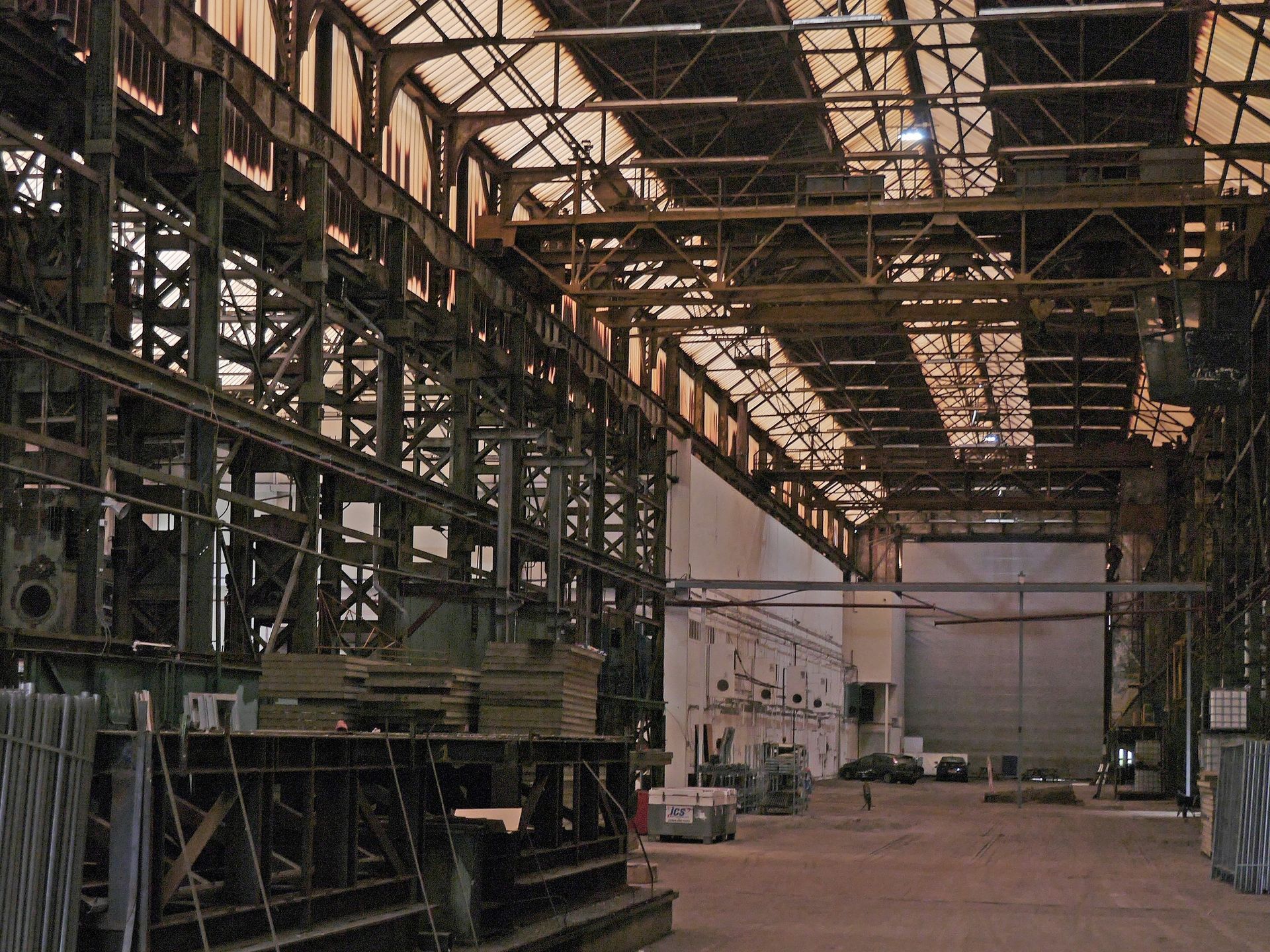 Interior of a large, industrial building with metal framework, machinery, and a high ceiling.