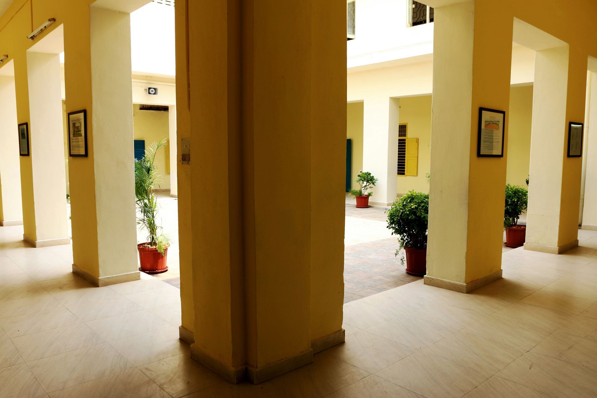 A long hallway with stairs, flanked by murals and illuminated by strip lighting, leading to an opening.
