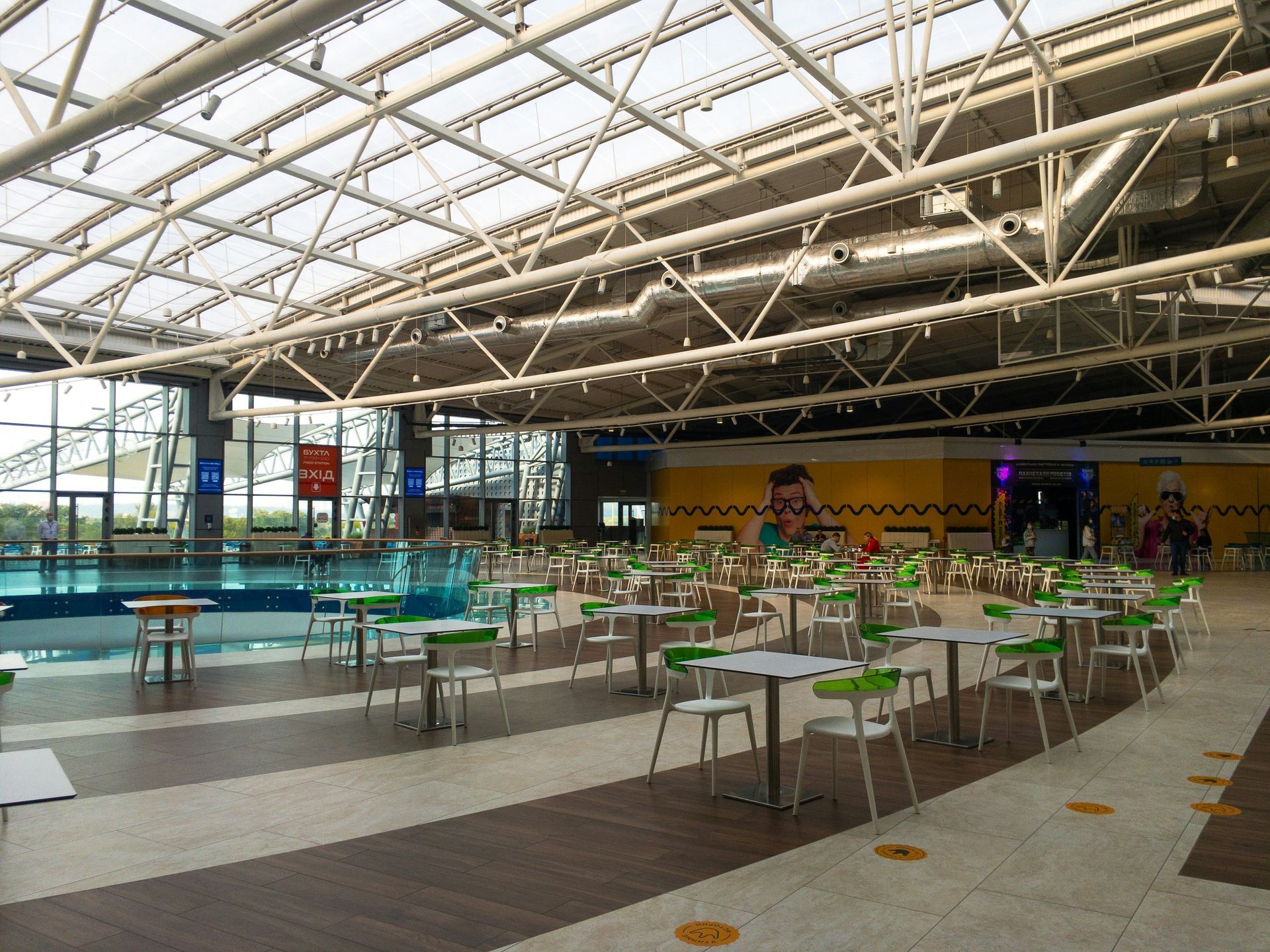 Indoor dining area with tables, chairs, and a pool visible through the glass.