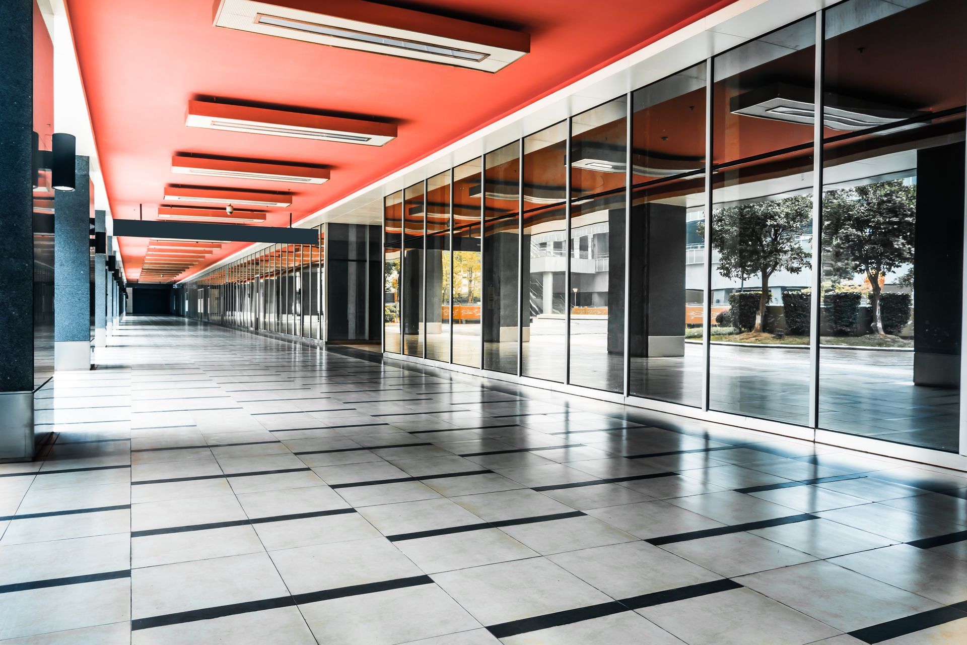 Empty hallway with red ceiling, large windows, and checkered tile floor.