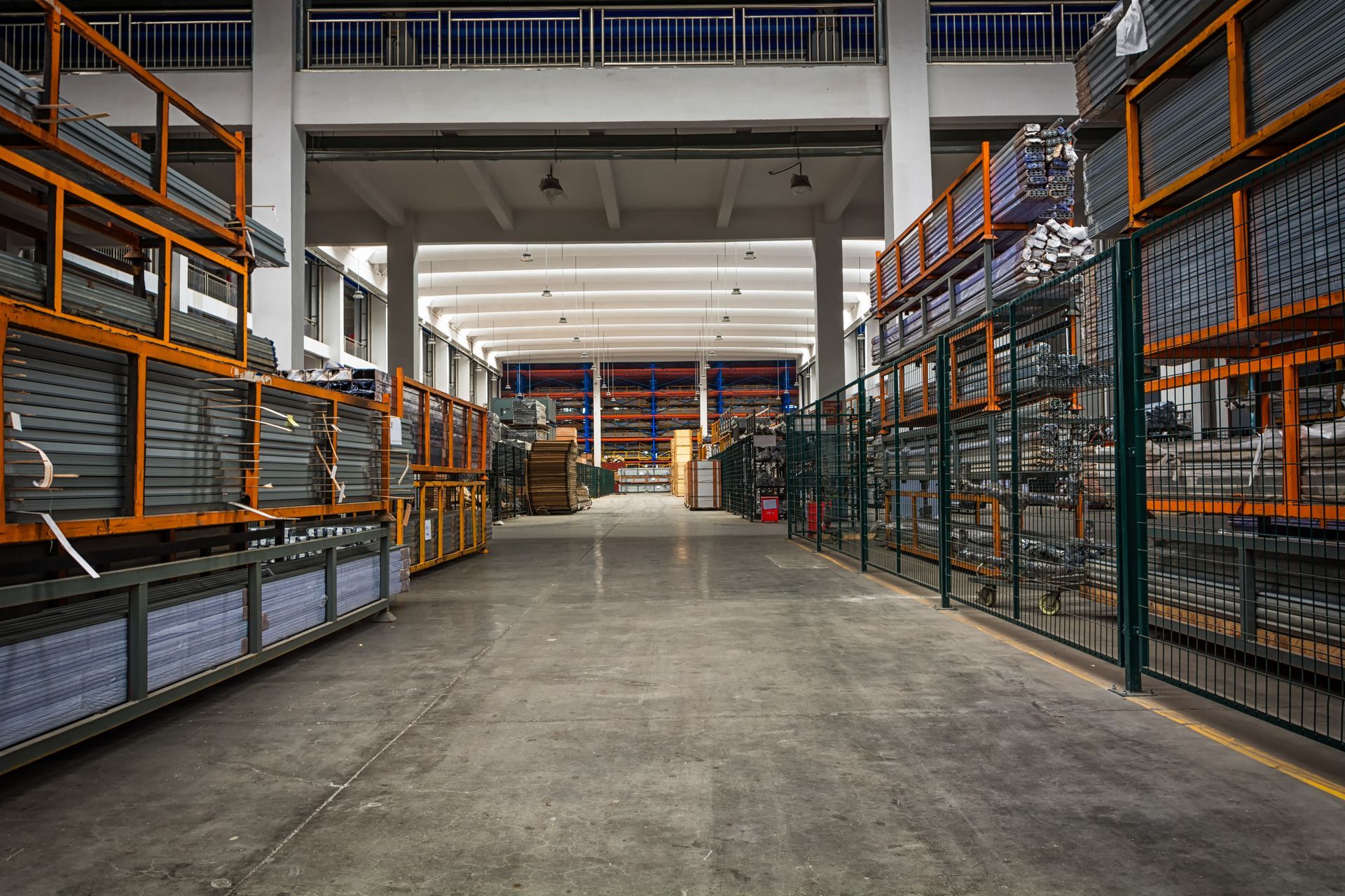 Warehouse interior with tall metal shelving, stacked with materials; concrete floor.