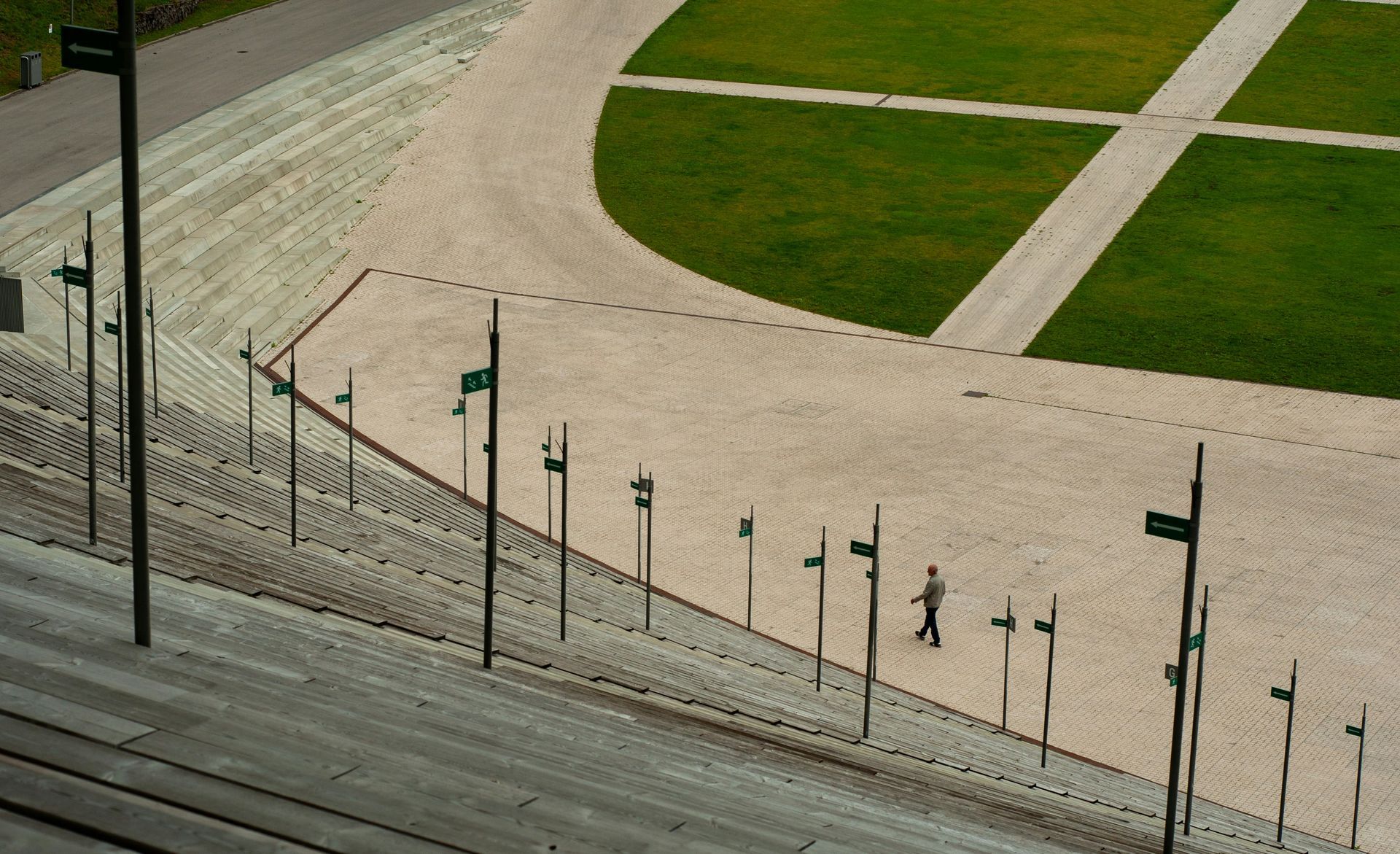 Stone steps and pathways lead to a green lawn. A person walks along a path.