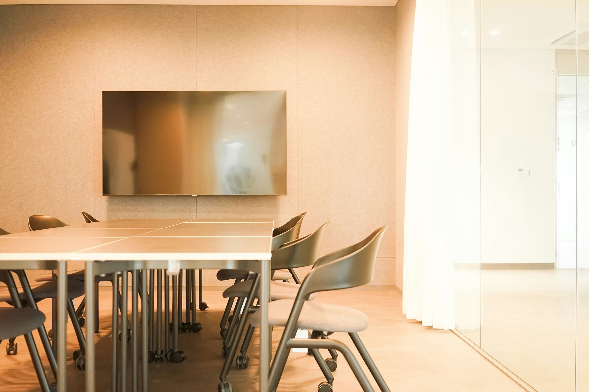 Conference room with table, chairs, large screen, and glass wall.