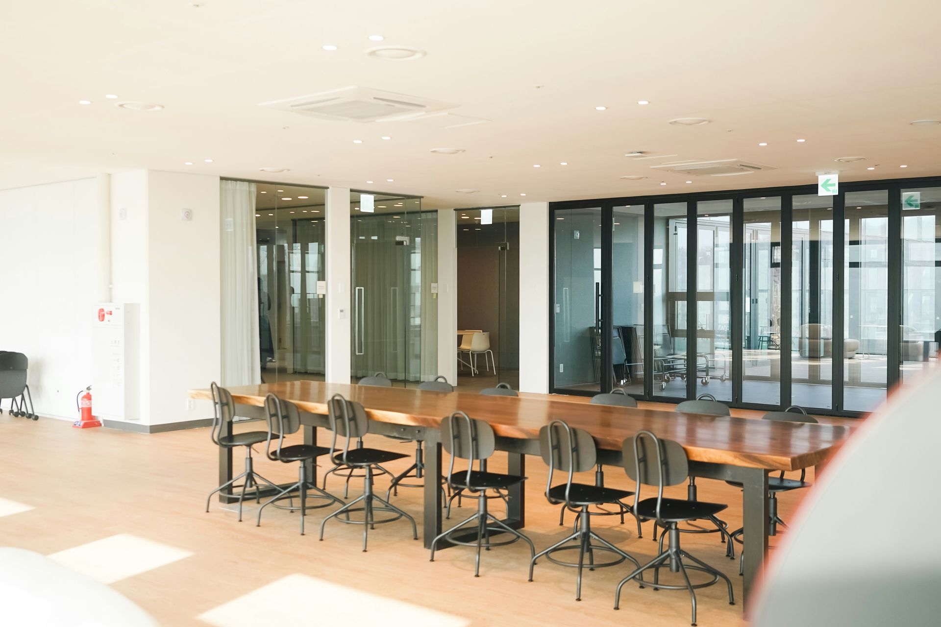 Large, bright conference room with long table, chairs, and glass walls; office setting.