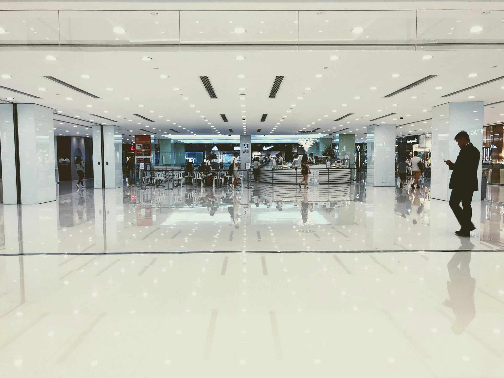 A person walks in a brightly lit mall with reflective, polished floors.