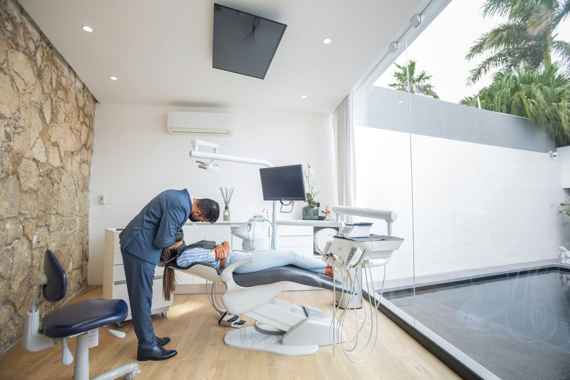 Dental chair in a bright room, with attached medical instruments and a window.