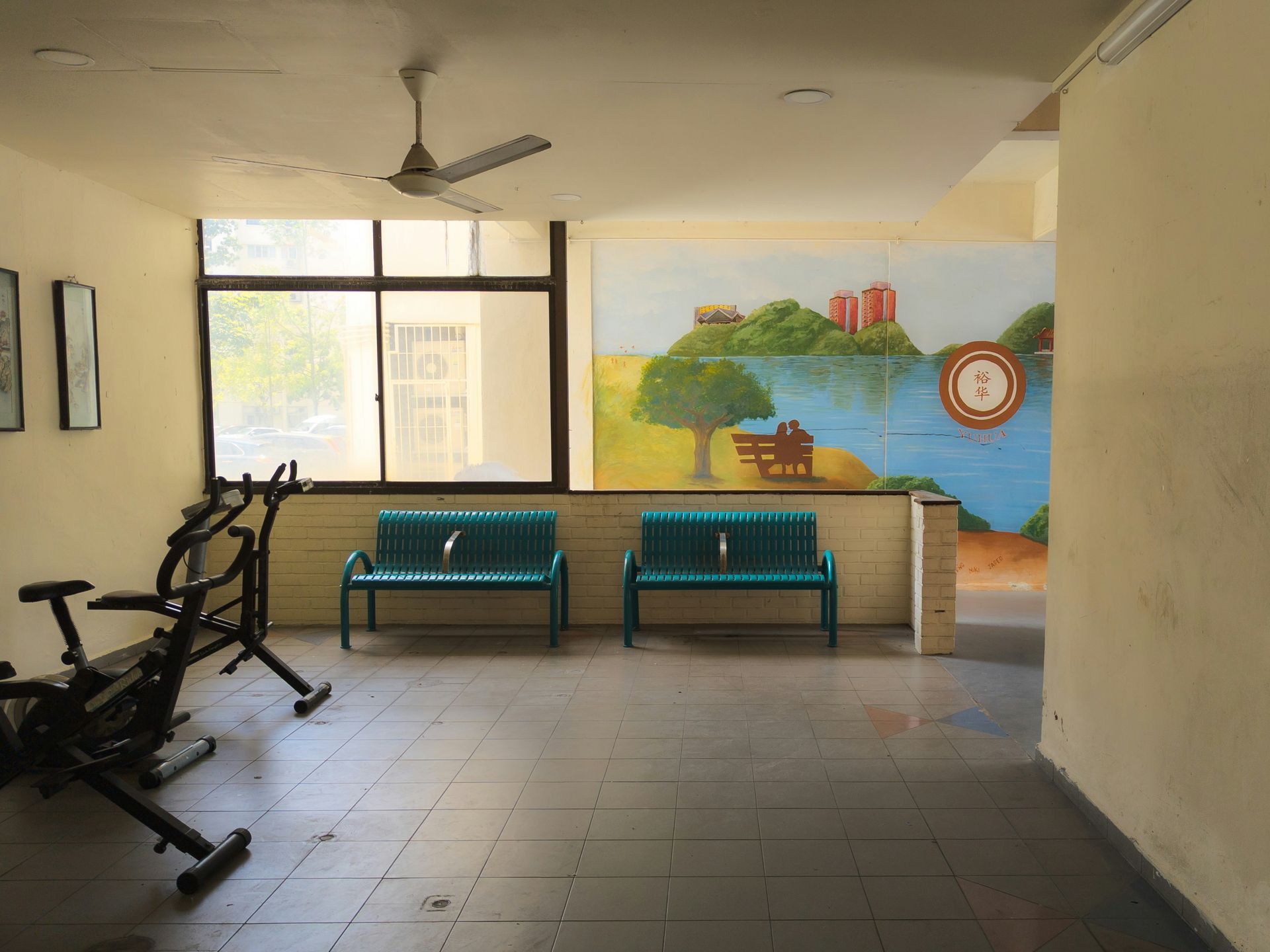 Indoor gym area with exercise bikes, benches, a mural, and a window.