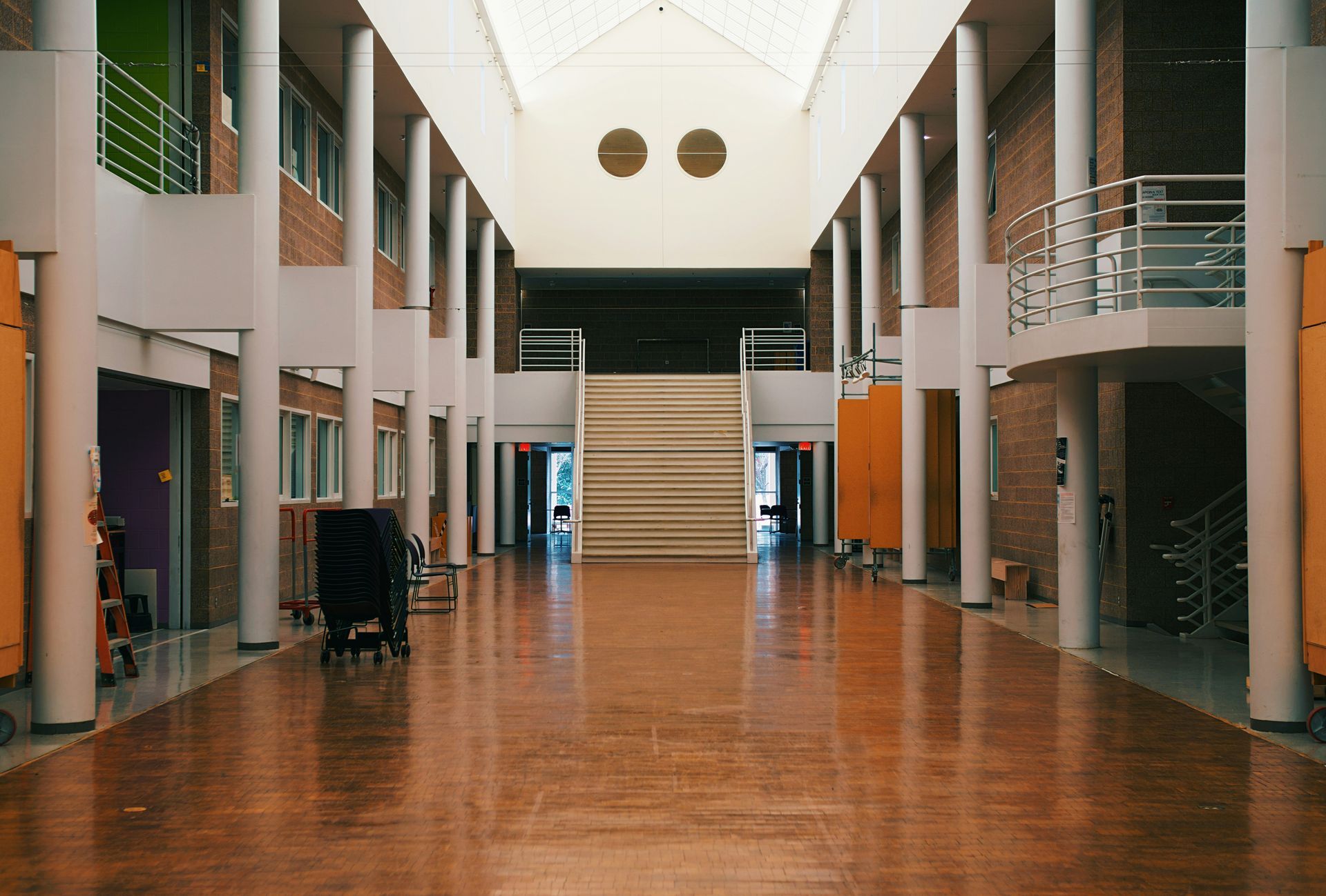 Interior hallway with wooden floor, columns, and stairs at the end.
