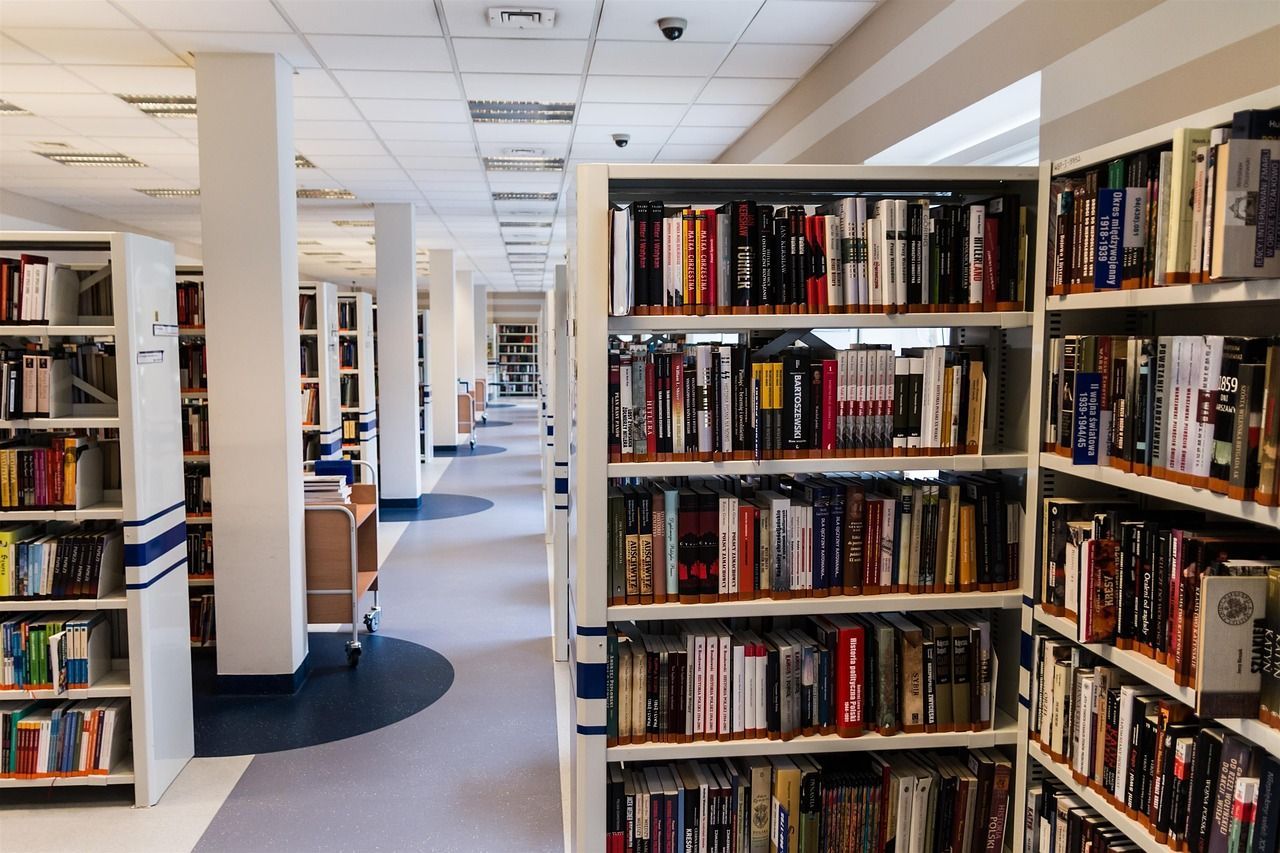 Library interior with rows of bookshelves, books, and a long hallway perspective.