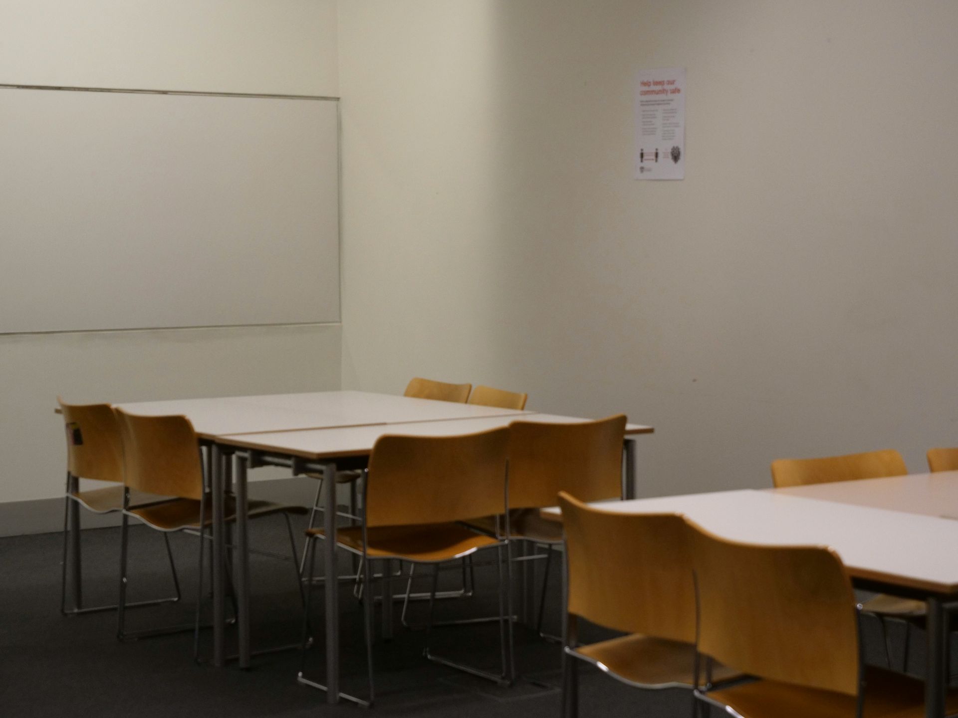 Empty classroom with rows of desks, windows, and natural light streaming in.