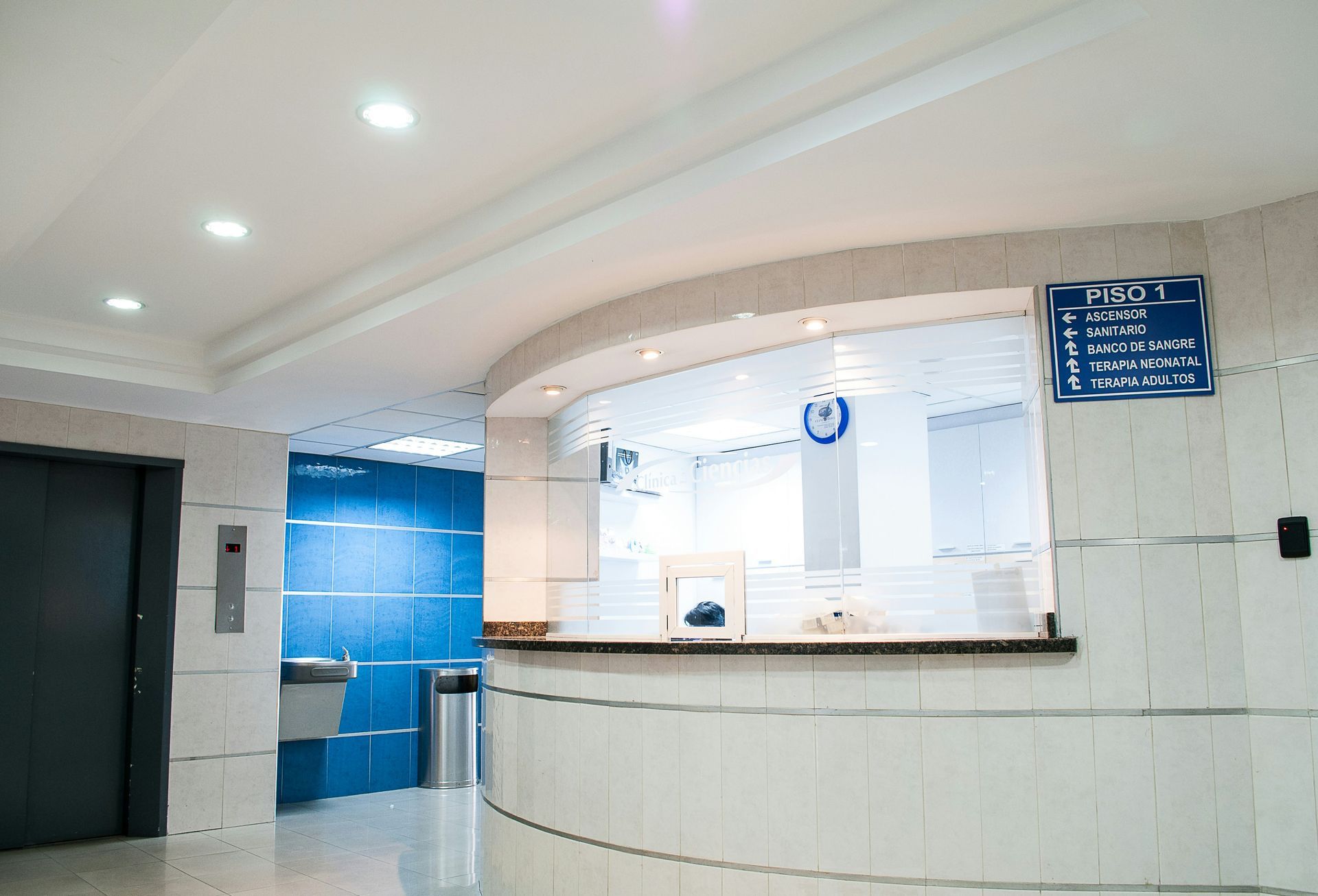 Reception area with curved white desk, blue wall, and signage.