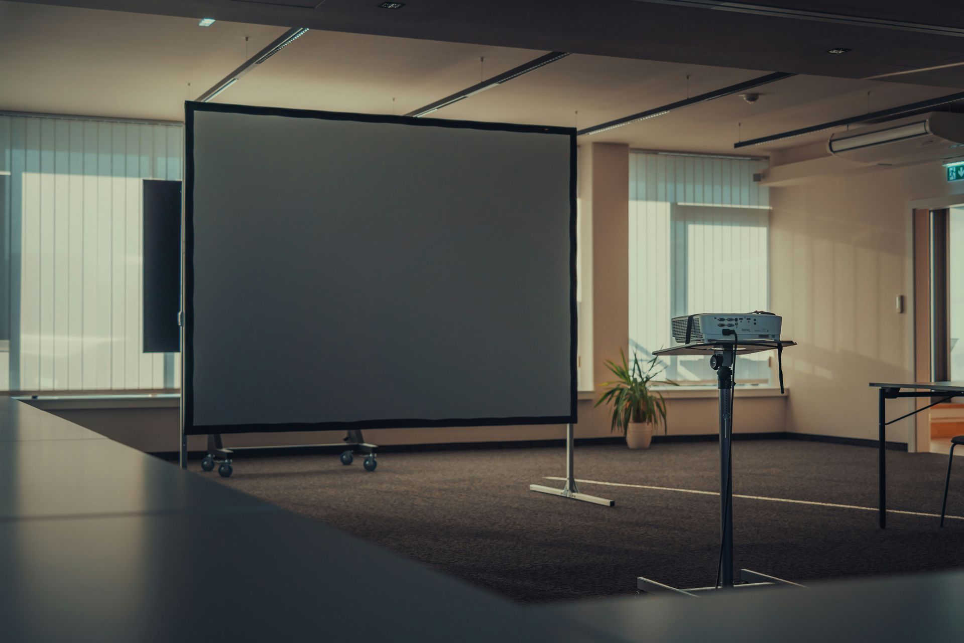 Empty conference room with projector, screen, and desk.