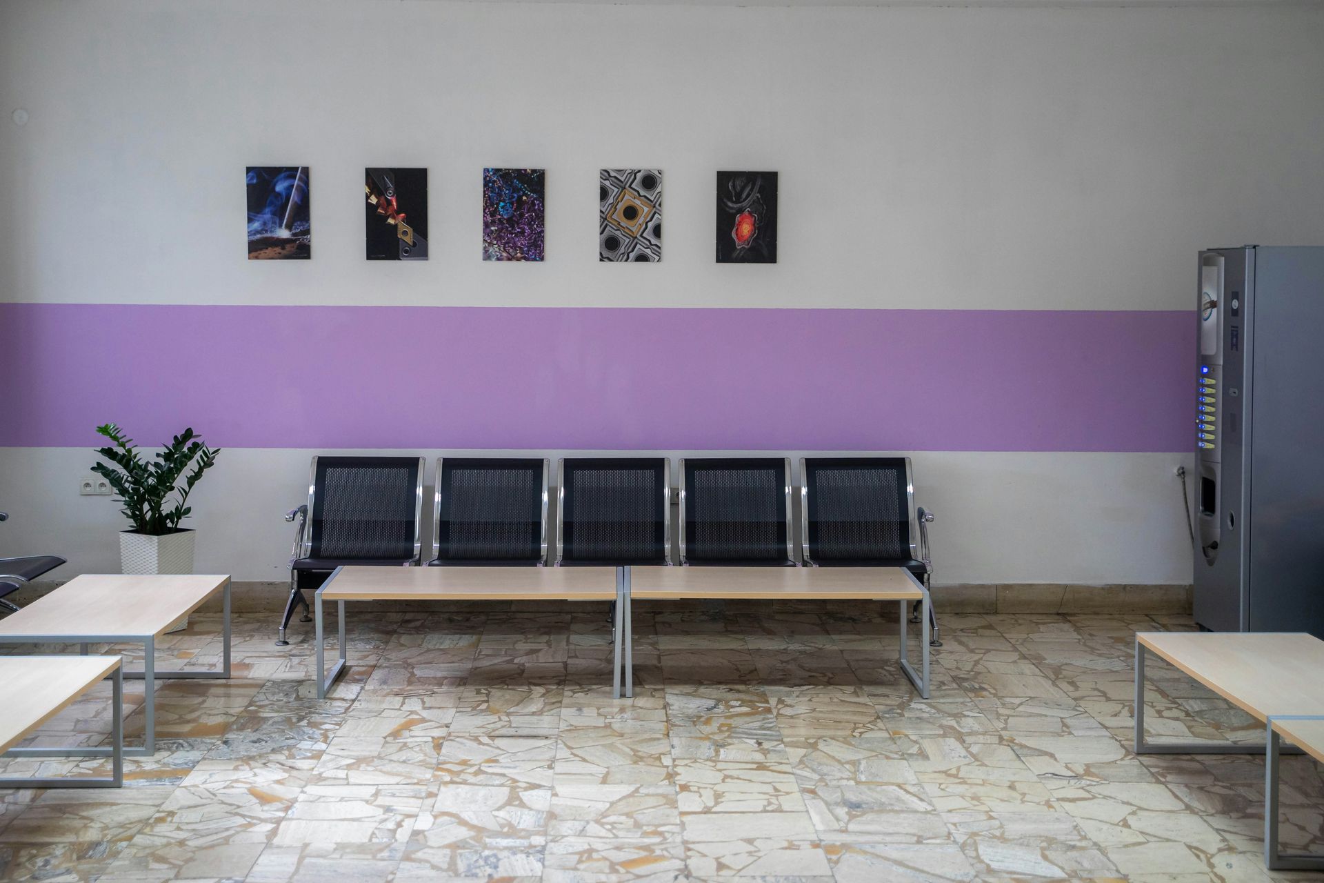 Waiting area with chairs, tables, art, and a purple stripe on the wall.