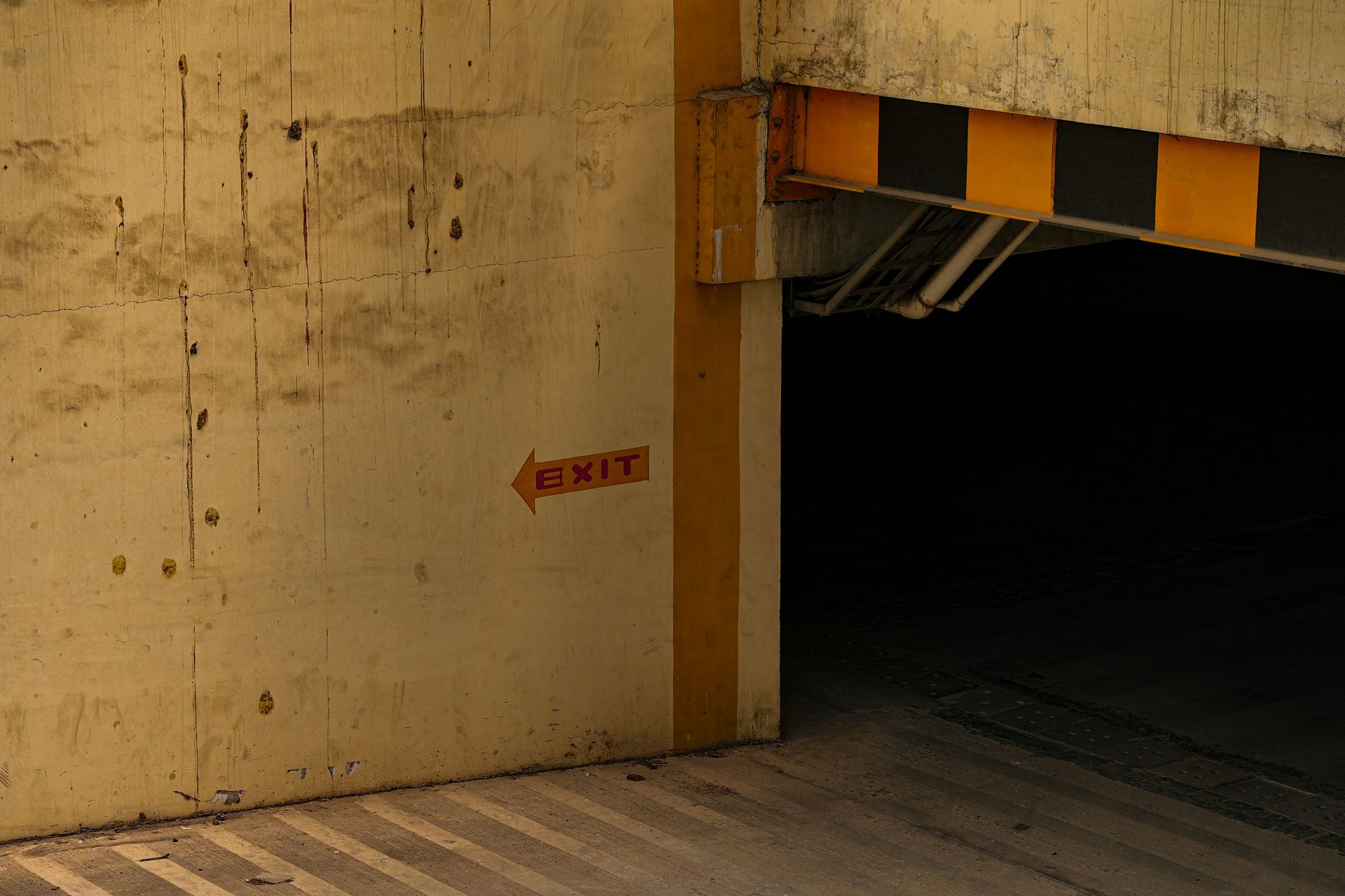 A warehouse worker in a yellow forklift moves a pallet of stacked items near a conveyor belt.