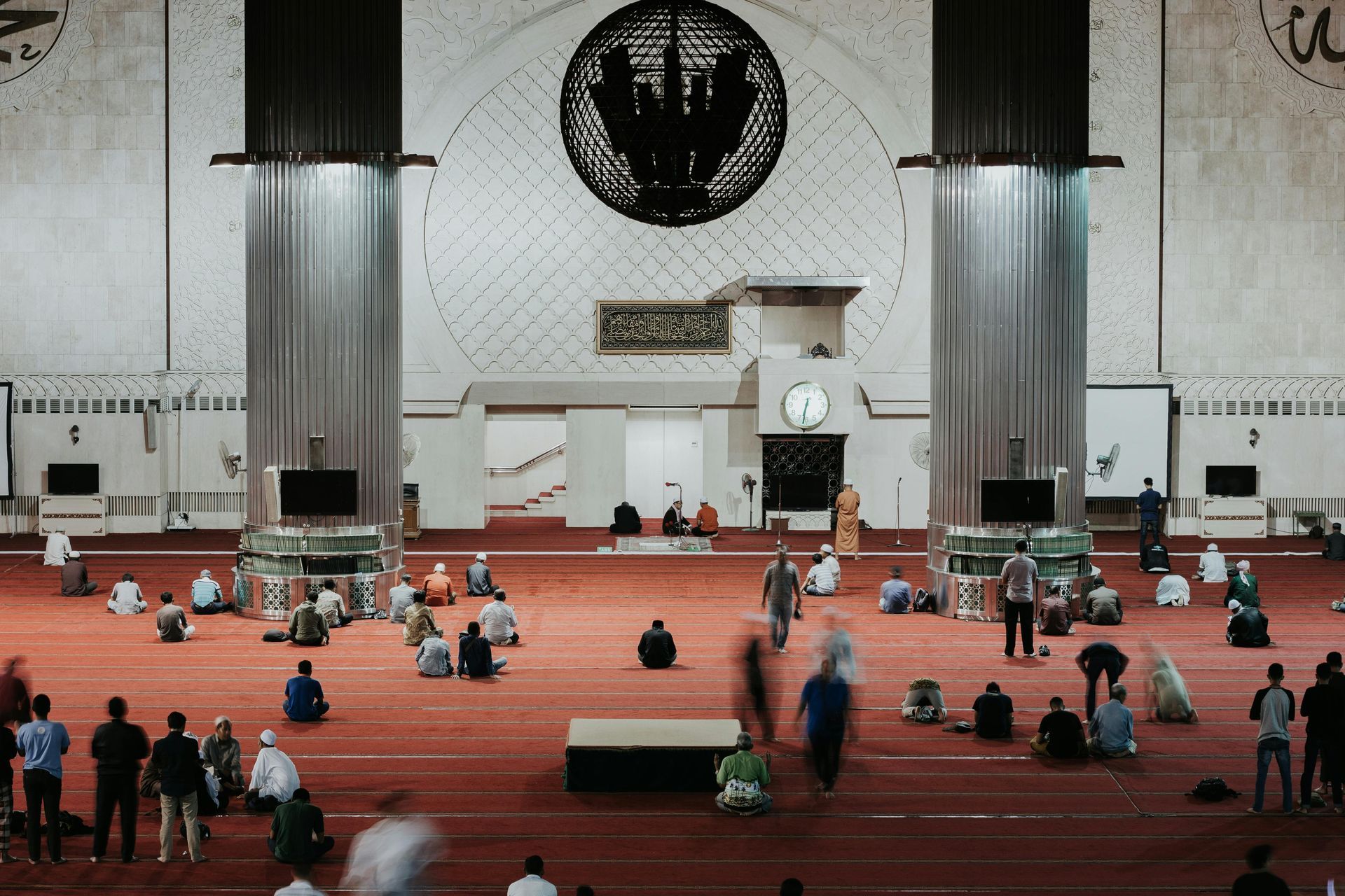 Indoor view with large windows overlooking a city with mountains; concrete and glass architecture.