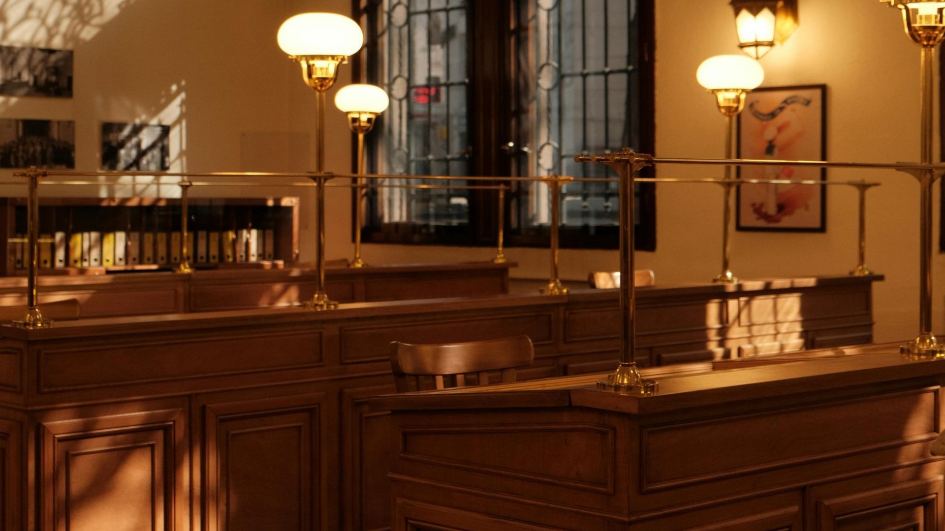 Bank teller booths with brass rails and globe lamps, interior shot.