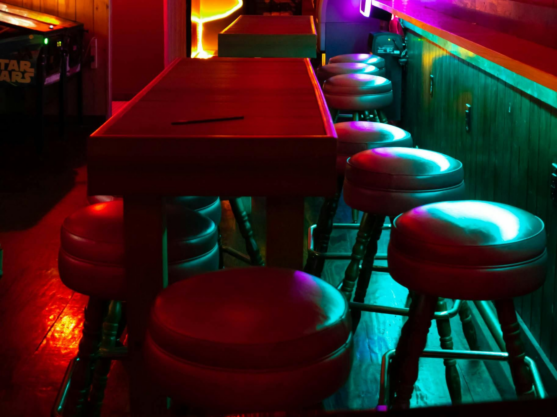 Boise Bar interior with stools, a long counter, and shelves filled with bottles, lit by amber lights.