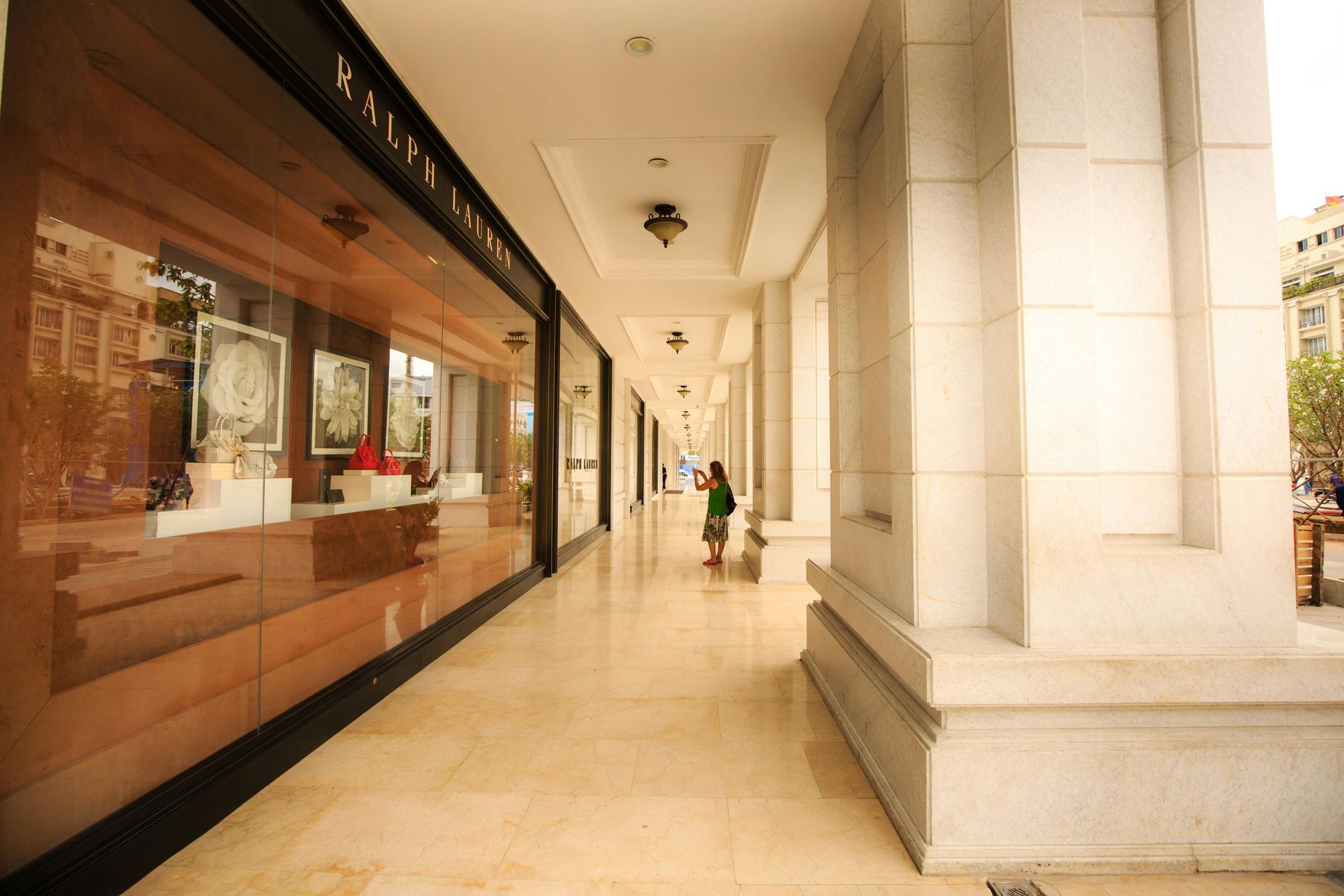Exterior of a luxury shop with glass display windows; child and dog walk down the walkway.