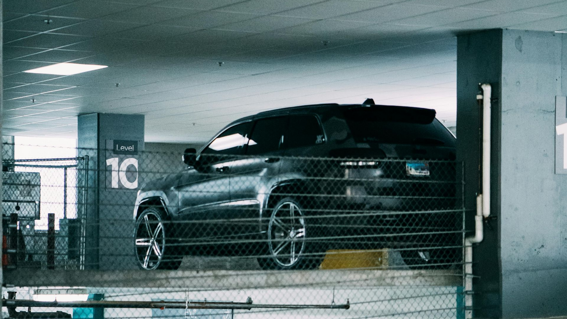 Black SUV parked in a Eagle's parking garage, near concrete pillars and metal netting to be cleaned at Noble Cleaning a cleaning and janitorial services