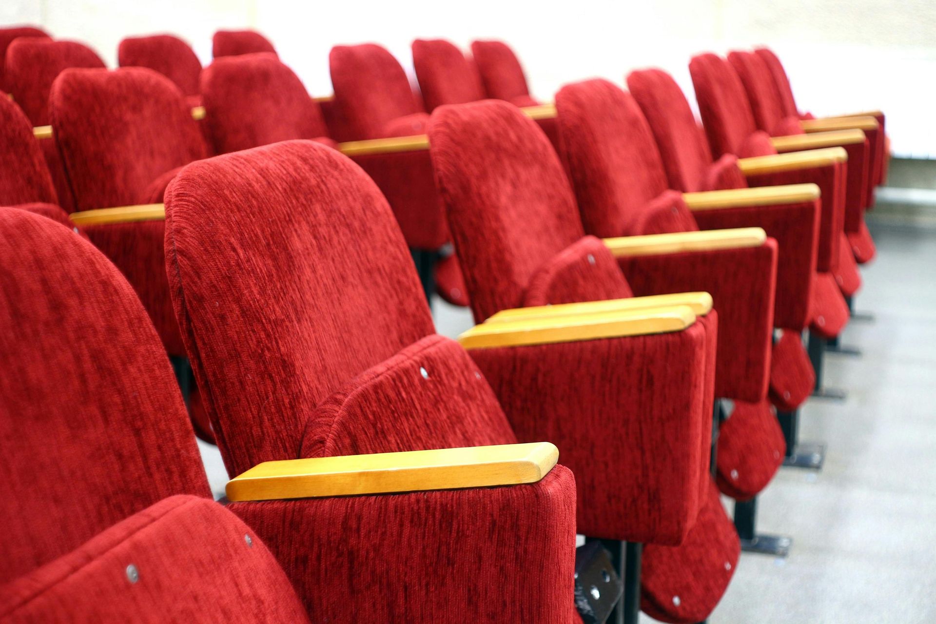 Rows of red velvet theater seats with wooden armrests.