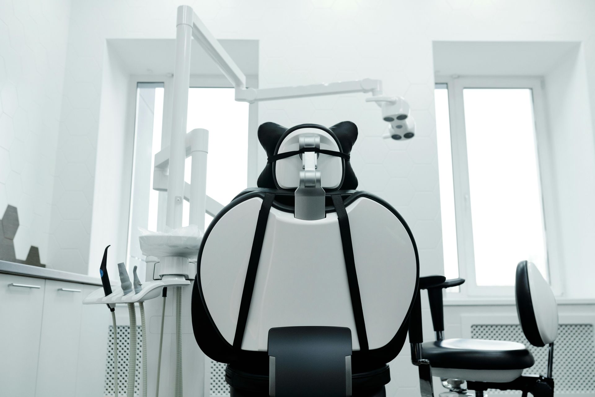 Dental chair in a bright room, with attached medical instruments and a window.