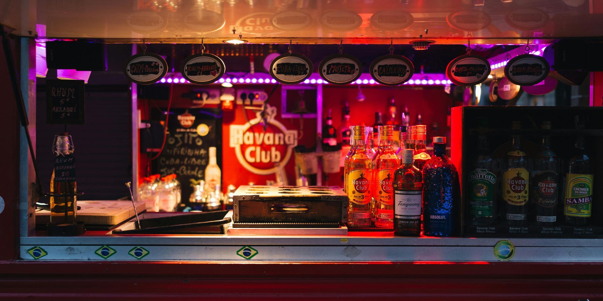Boise Bar counter with liquor bottles and a Havana Club sign, bathed in red and purple lights.