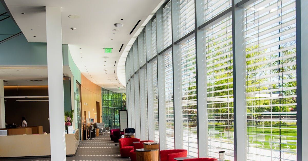 Interior view of a modern building with large windows, seating, and a reception desk.