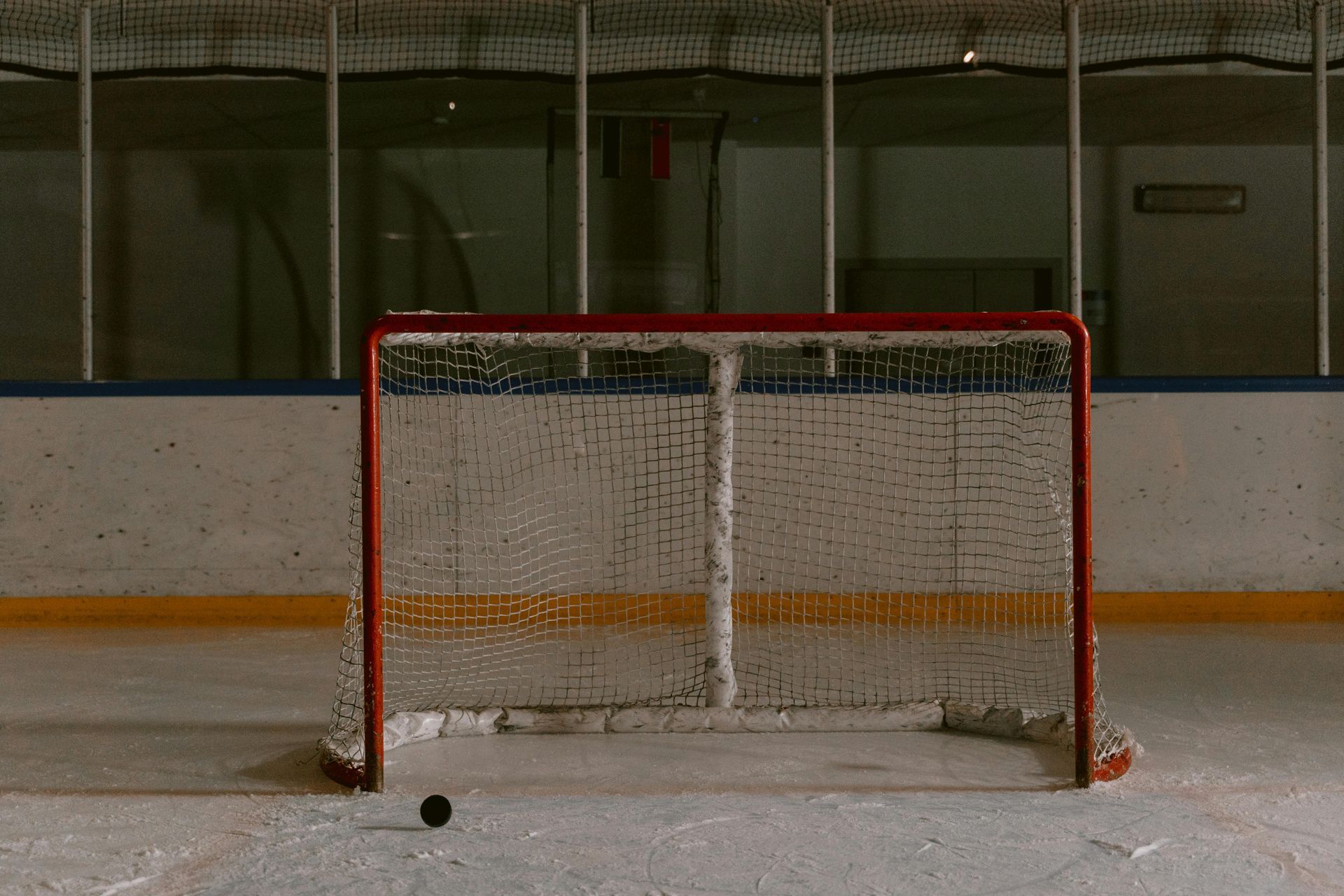 Hockey puck in front of an empty ice hockey goal.
