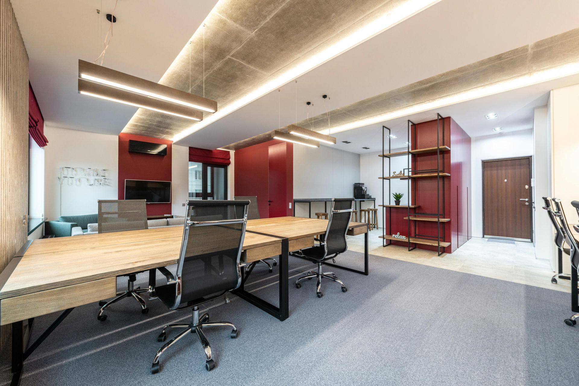 Modern office space with conference table, burgundy accents, and a textured ceiling.