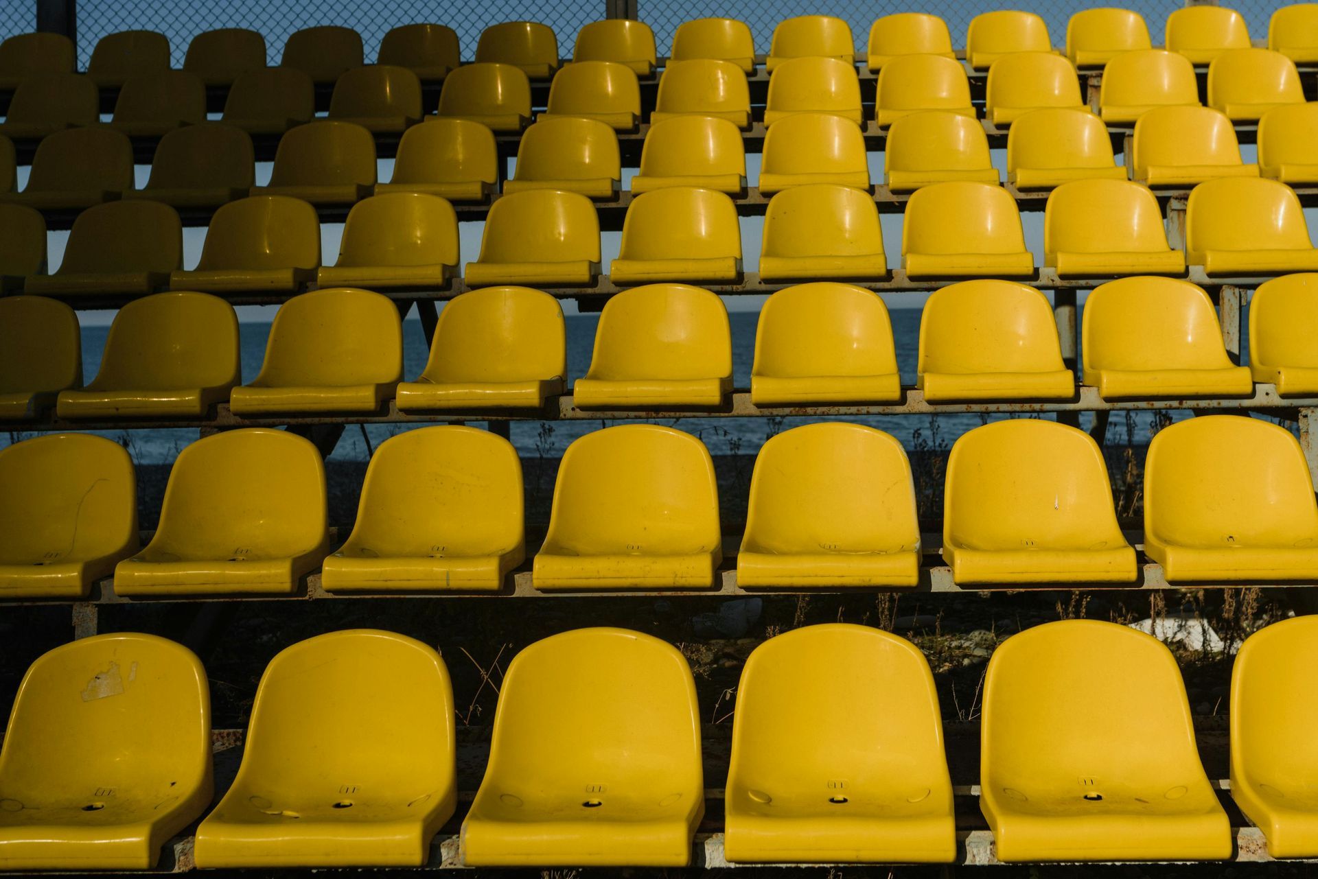 Yellow stadium seating, rows of empty seats, shaded from top to bottom.