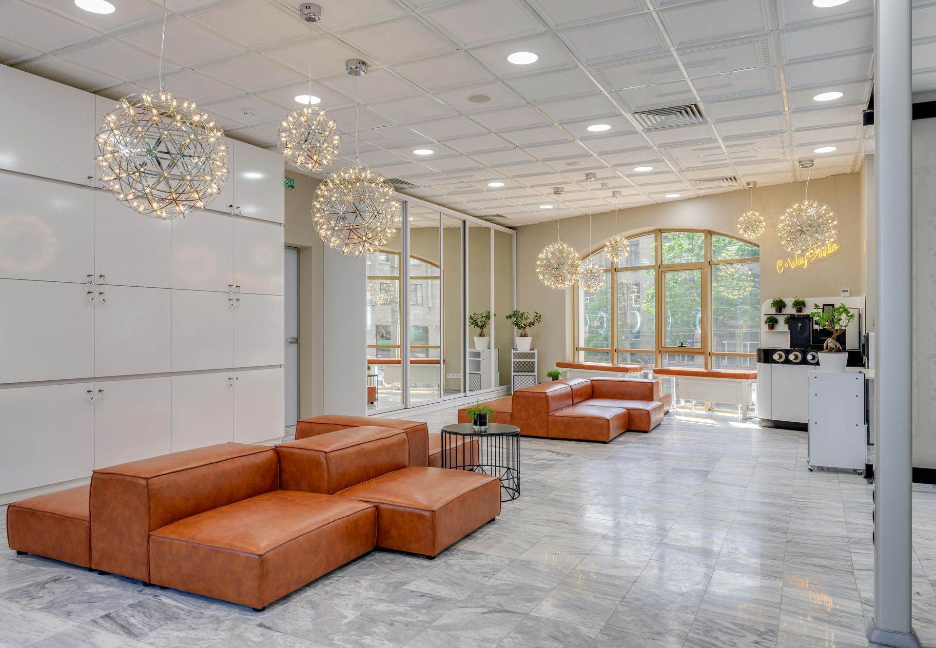 Modern lounge area with brown leather sofas, spherical lights, and large windows.