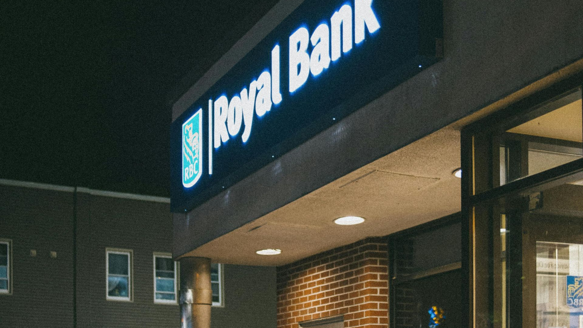Royal Bank illuminated sign above a brick building entrance at night.