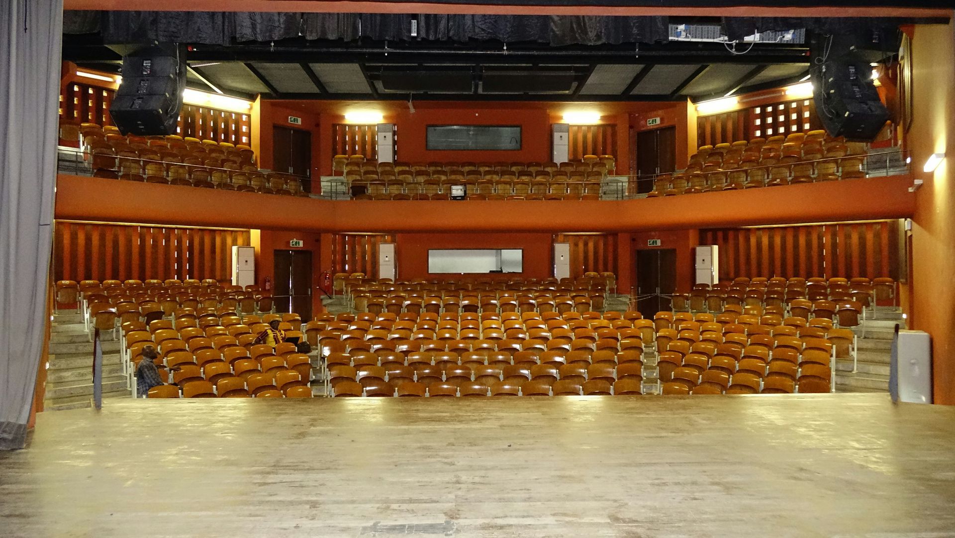 Rows of empty chairs face a stage in a large, empty conference room.