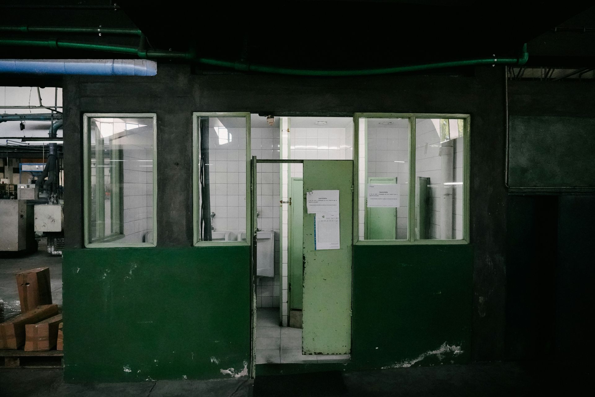Green and gray industrial office space with windows and a door, appearing old and unused.