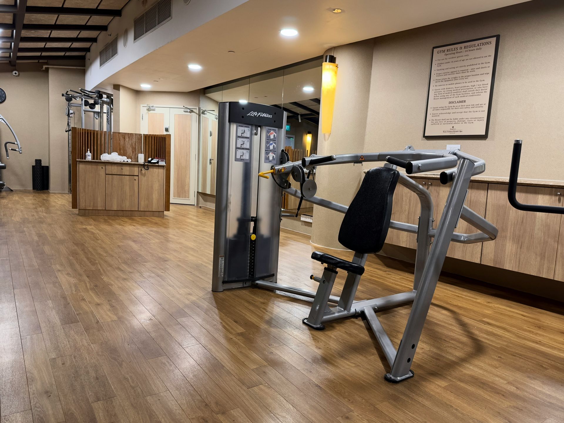 Gym interior with weight machine on wood floor.